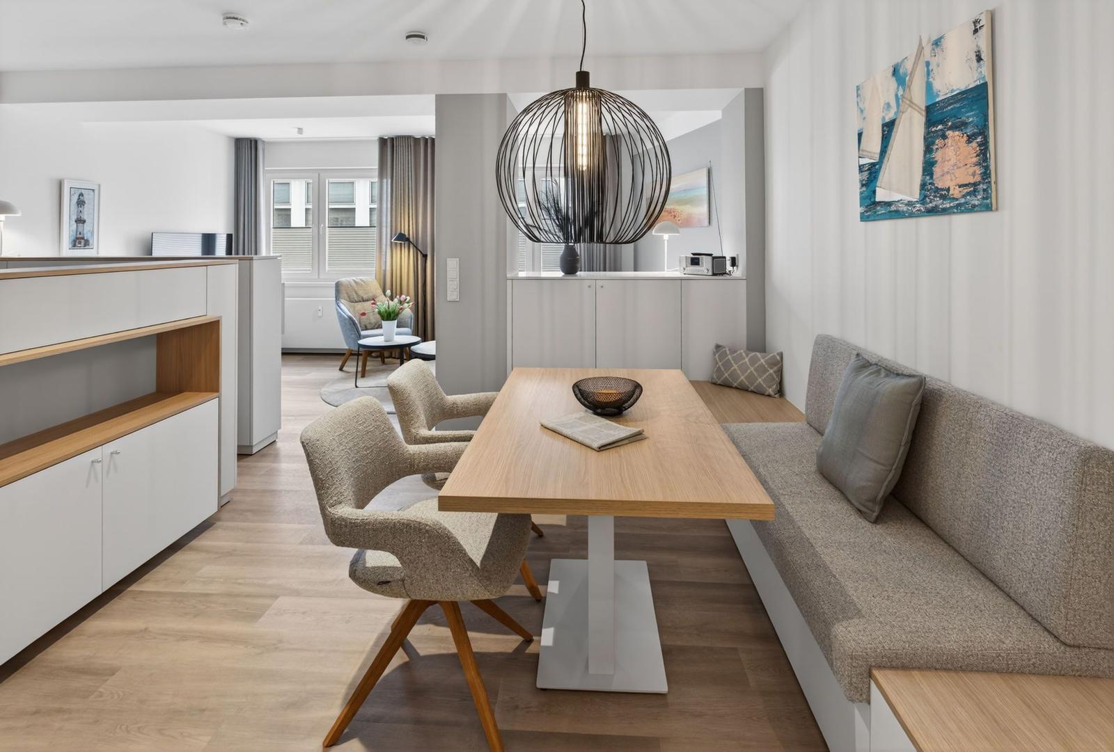 Essbereich mit Holztisch, Sitzbank und moderner Pendellampe.