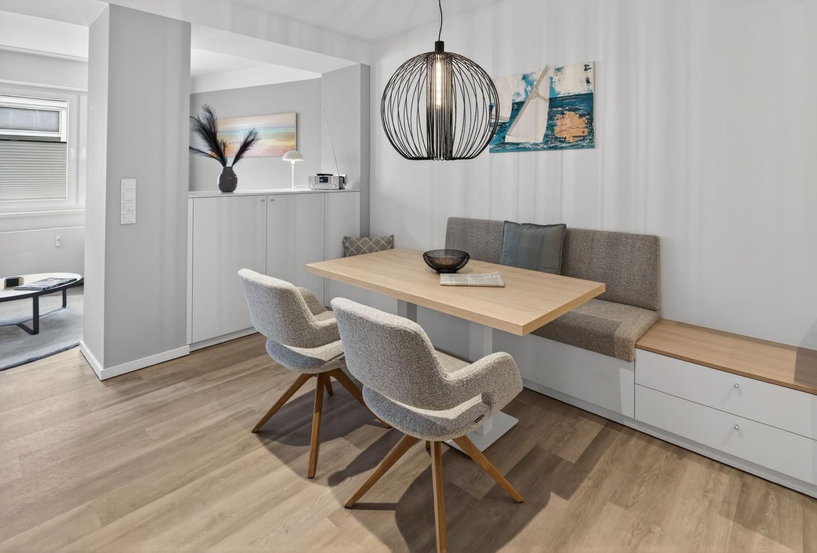 Essbereich mit Holztisch, zwei Stühlen und Sitzbank an der Wand.