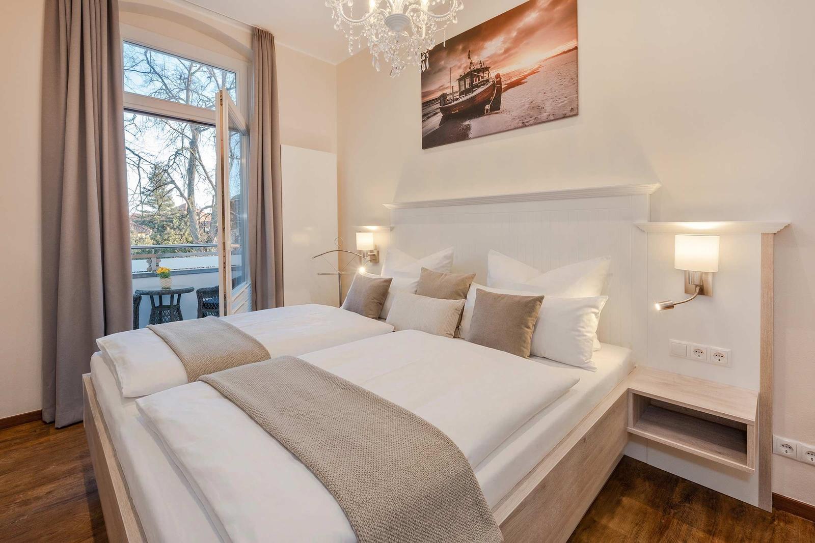 Schlafzimmer mit Doppelbett, Fenster und Wandbild. Deckenleuchte und Nachttische.