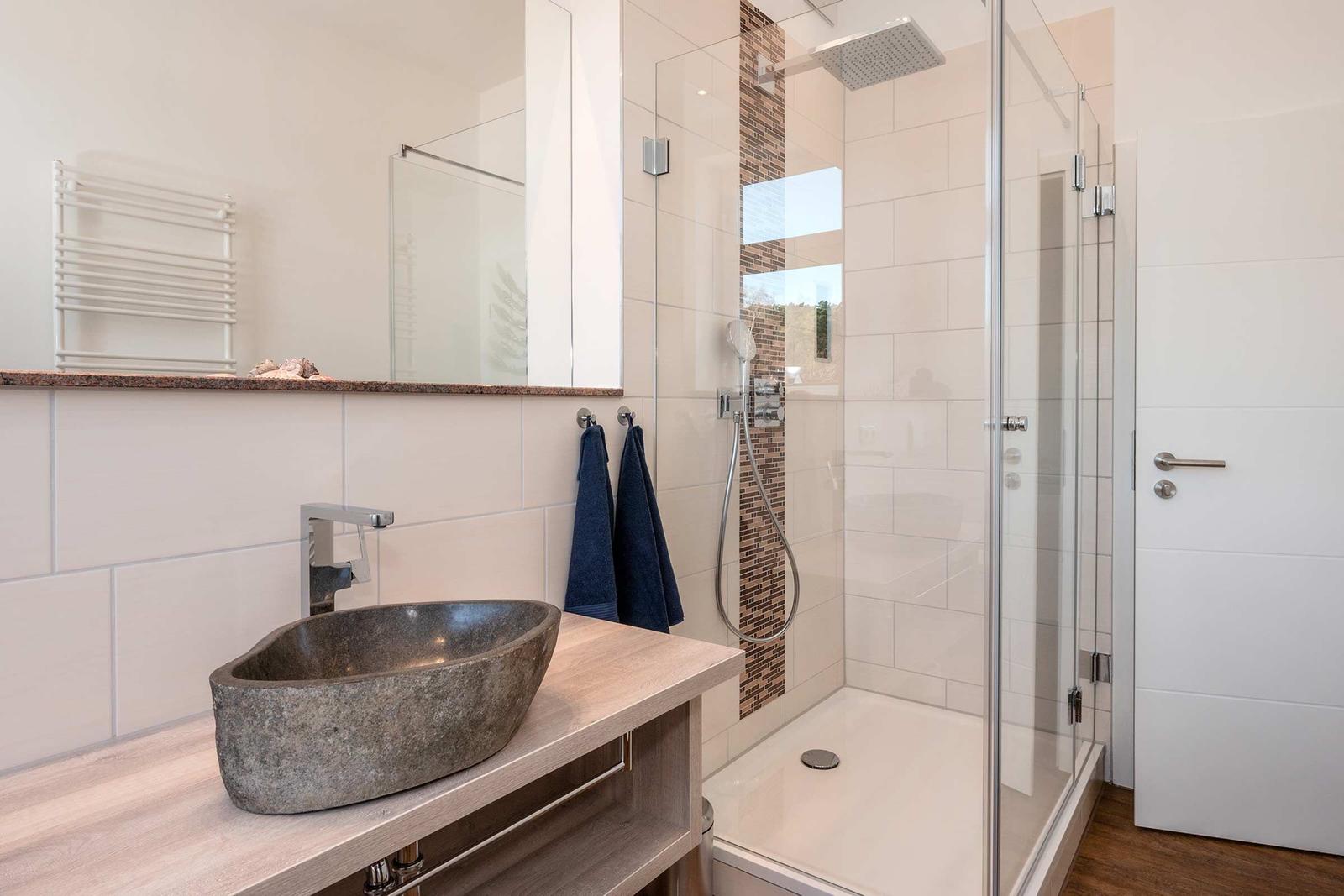 Badezimmer mit Dusche, Waschtisch und Spiegel