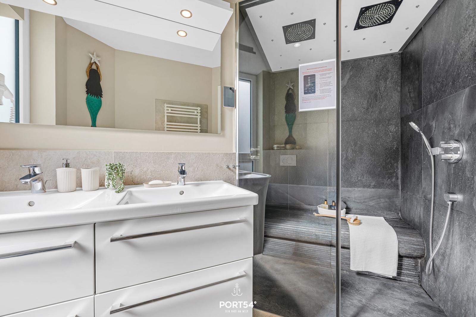 Badezimmer mit Dusche, Waschbecken und Spiegel
