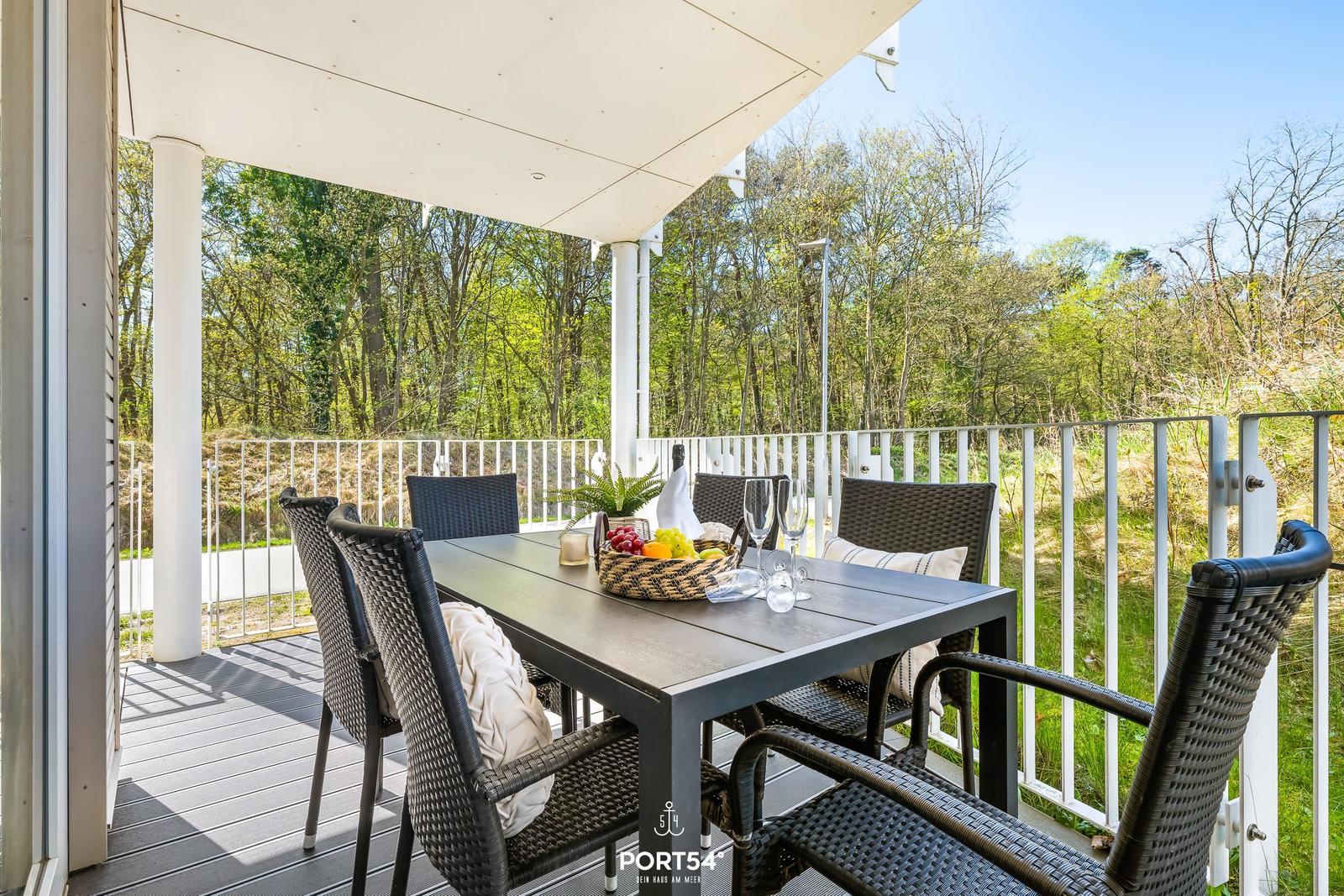 Terrasse mit Tisch, Stühlen und Blick in den Wald.