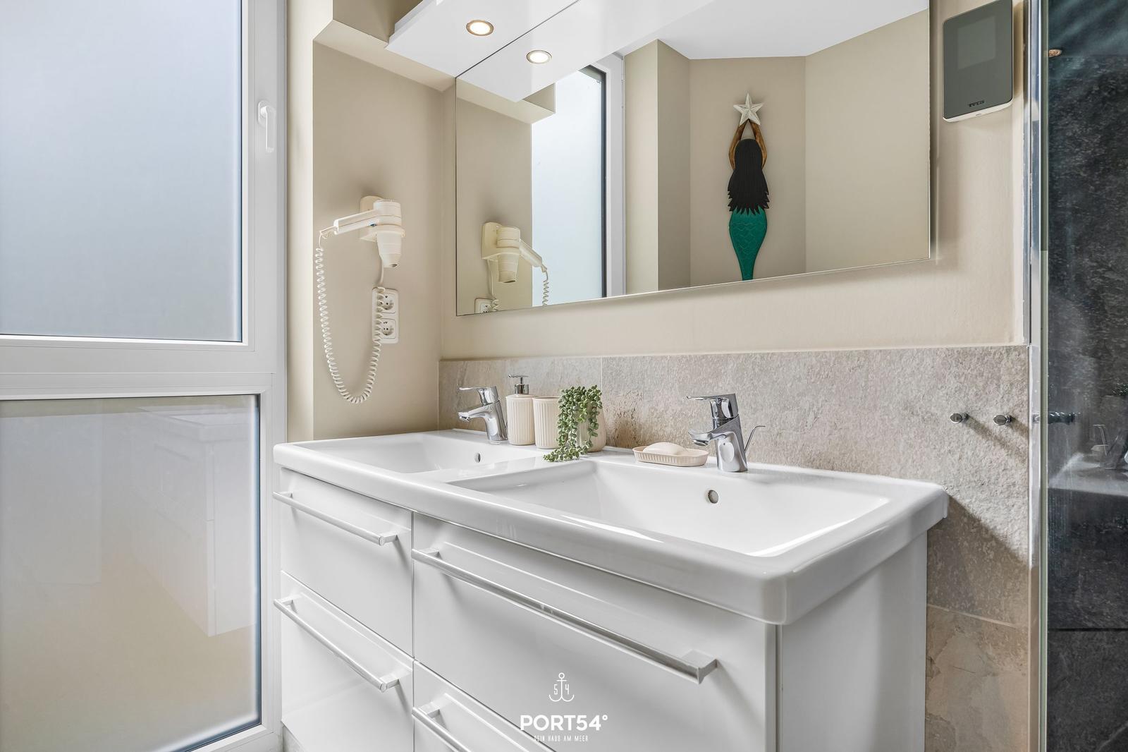 Badezimmer mit Doppelwaschbecken, Spiegel und Dusche