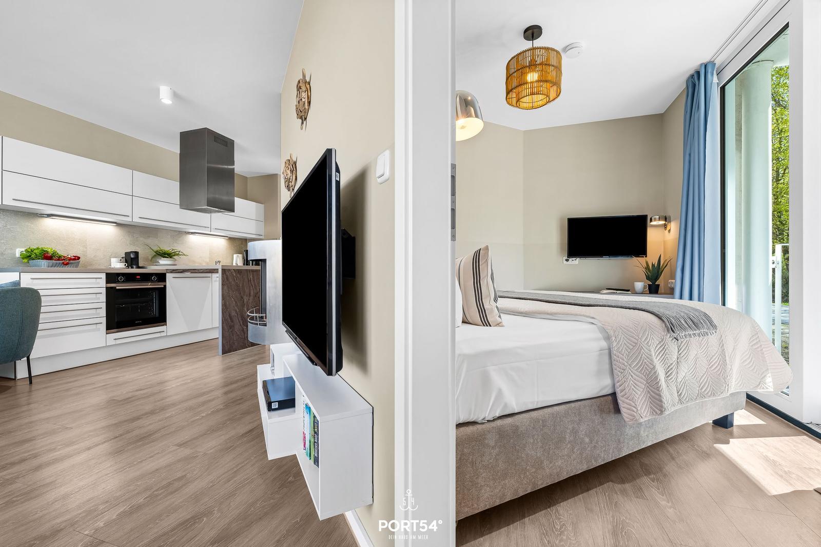Küche mit moderner Einbauküche und Schlafzimmer mit Doppelbett und Fenster.