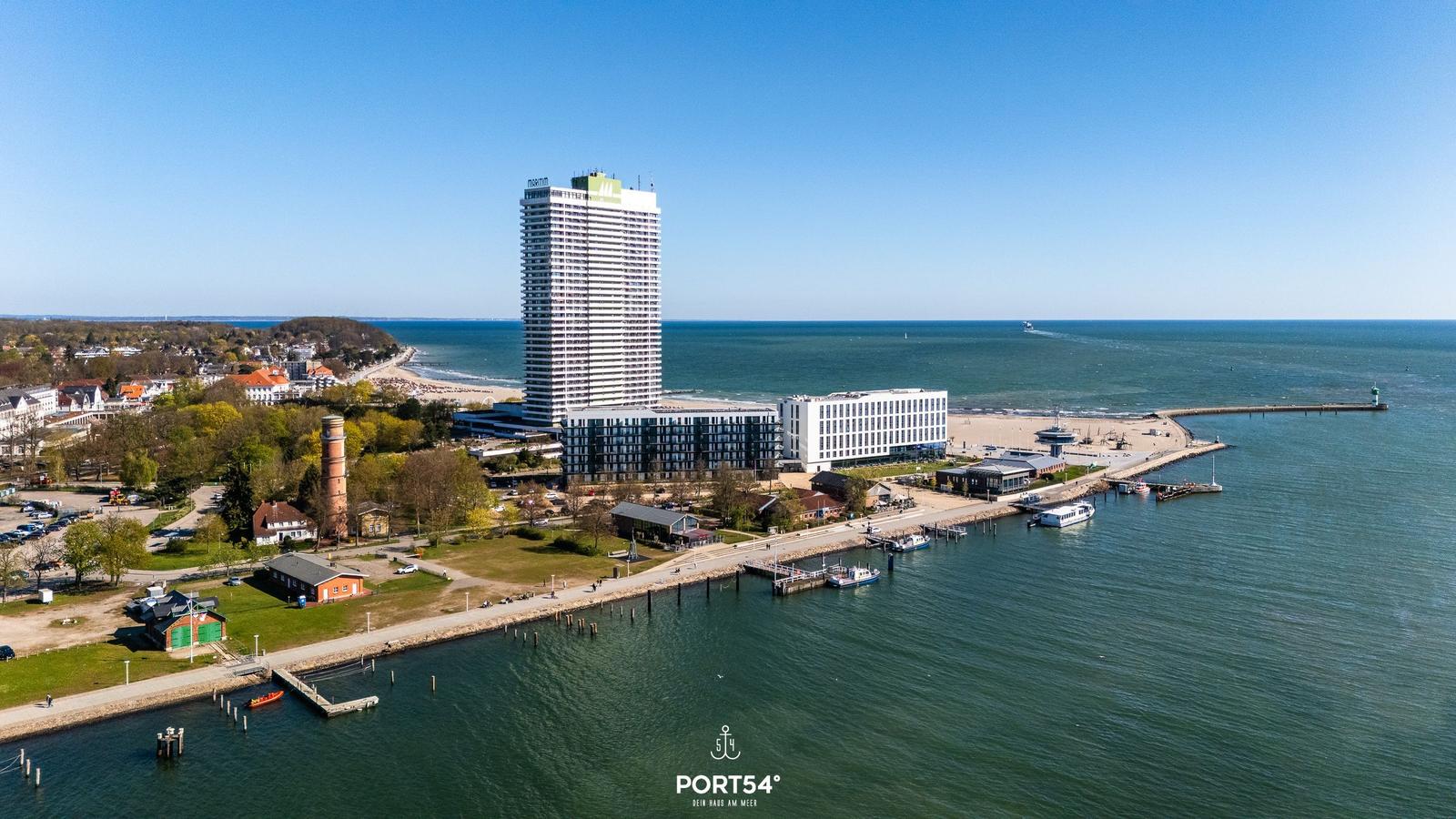 Hochhaus am Strand mit Pier und Bootshafen an der Küste.