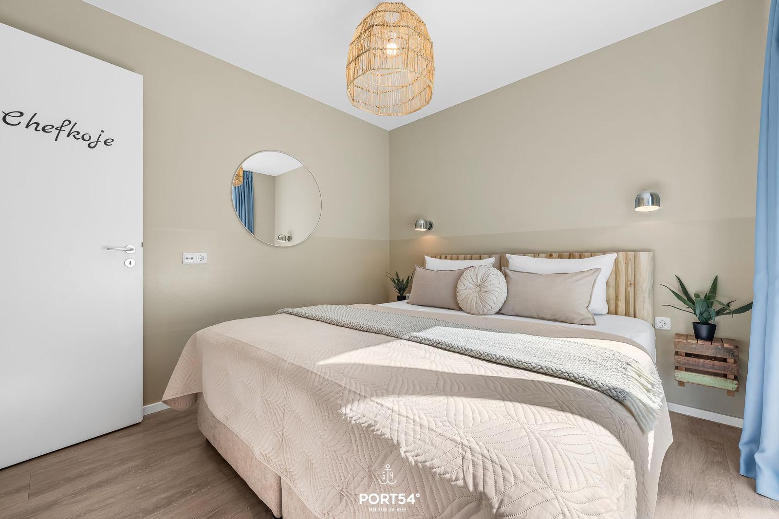 Schlafzimmer mit Bett, Spiegel und Deckenleuchte.
