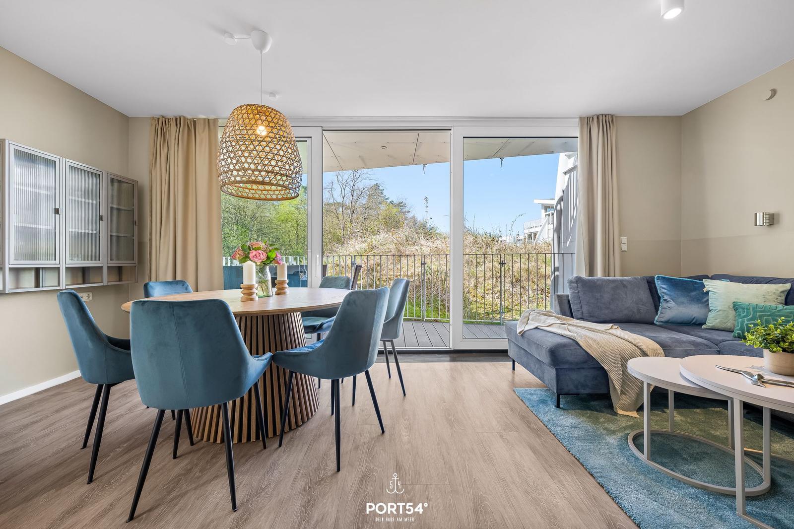 Essbereich mit Tisch und Stühlen, Wohnbereich mit Sofa und Blick auf Balkon.