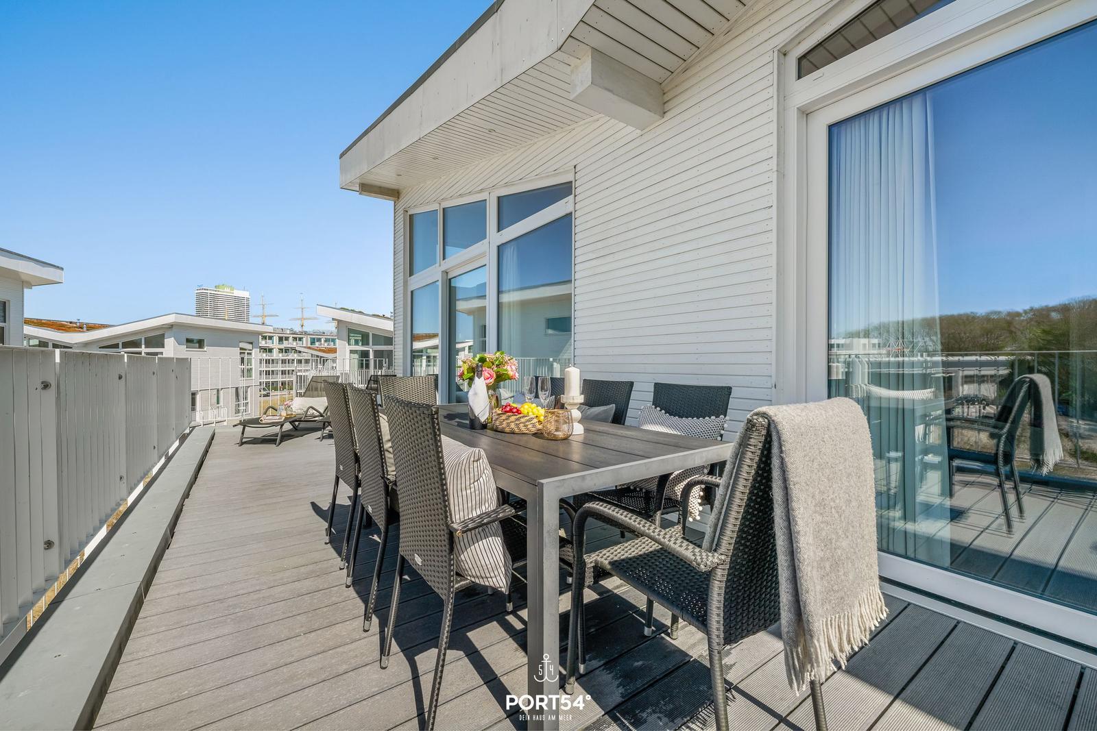 Terrasse mit Esstisch, Stühlen und Blick auf das Meer.