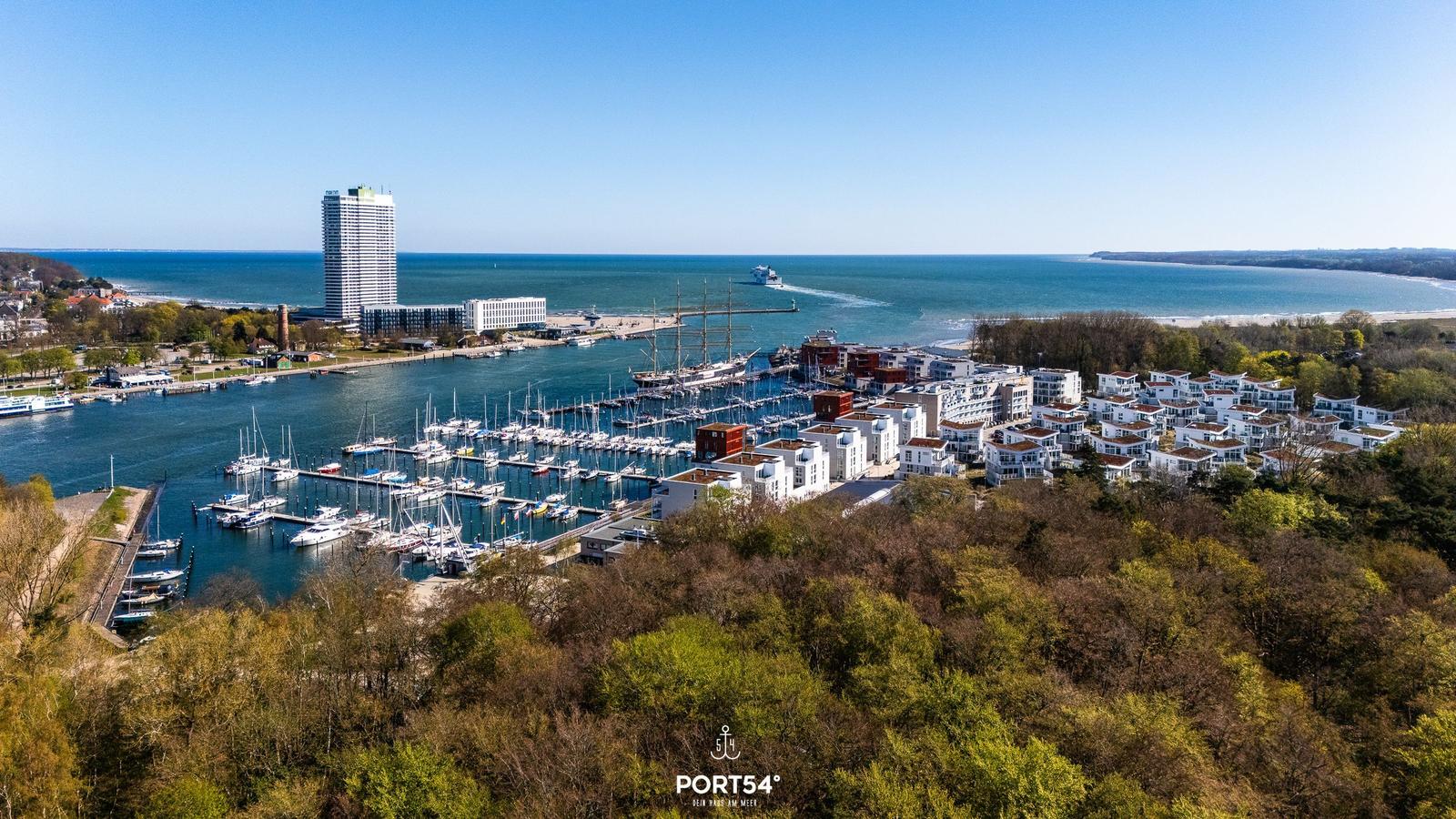Hafen mit Yachten, modernen Gebäuden und Blick aufs Meer.