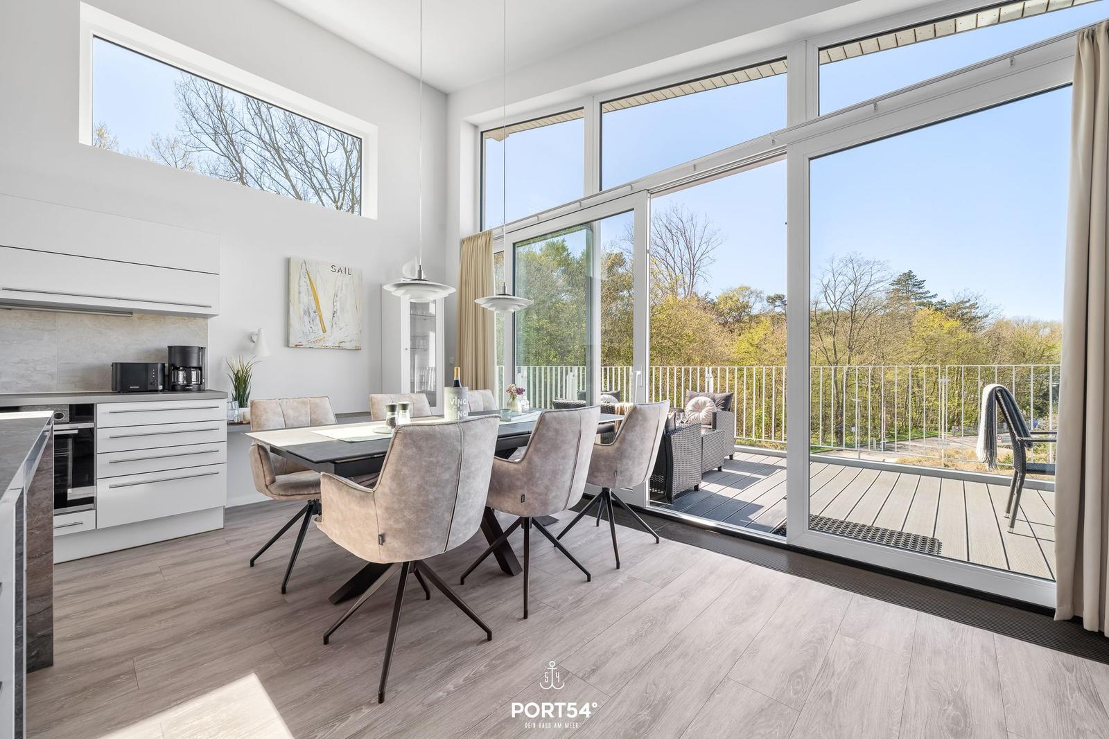 Modernes Esszimmer mit großem Fensterblick auf Balkon und Wald.