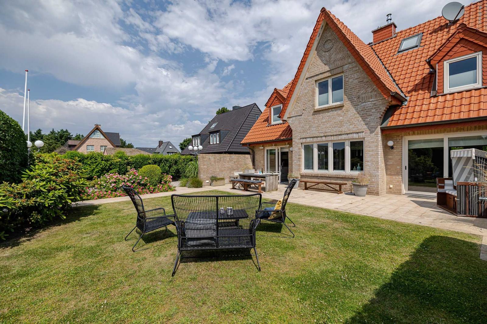 Haus mit Garten, Terrasse und Sitzgelegenheiten unter freiem Himmel.