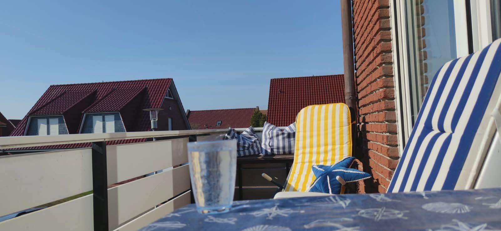 Terrasse mit Stühlen und Tisch. Im Hintergrund sind Häuser mit roten Dächern zu sehen.