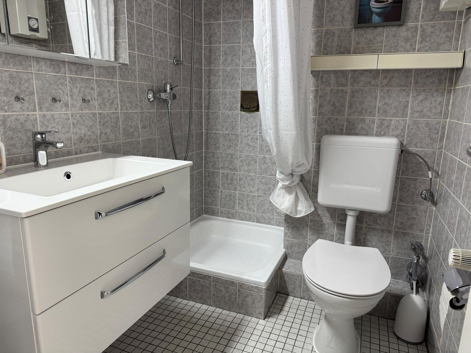 Badezimmer mit Dusche, Toilette und Waschbecken
