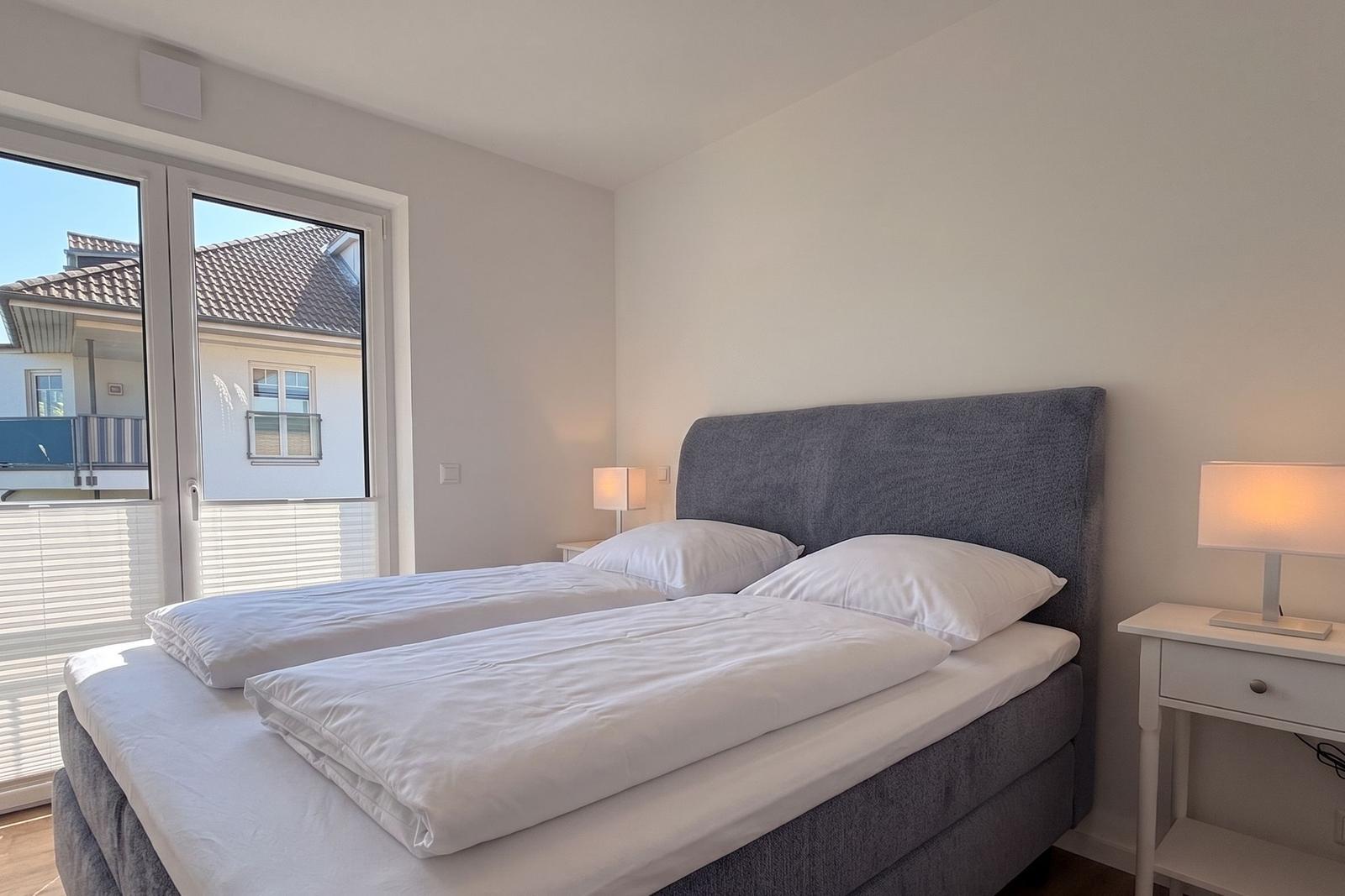 Schlafzimmer mit Doppelbett, Nachttisch und Fenster zur Aussicht.