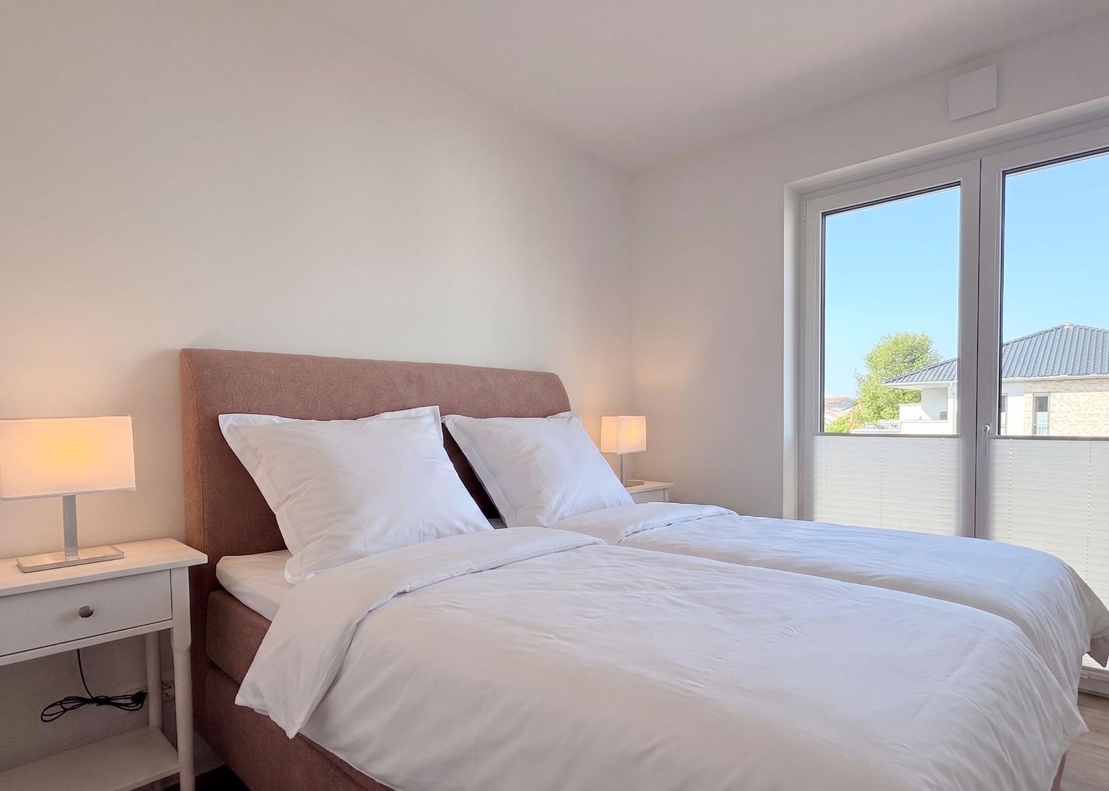 Schlafzimmer mit Doppelbett, Nachttischen und Fenster zur Aussicht.