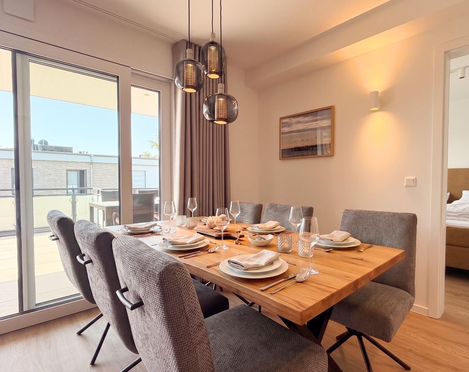 Esszimmer mit Holztisch, sechs Stühlen und Blick auf Balkon.
