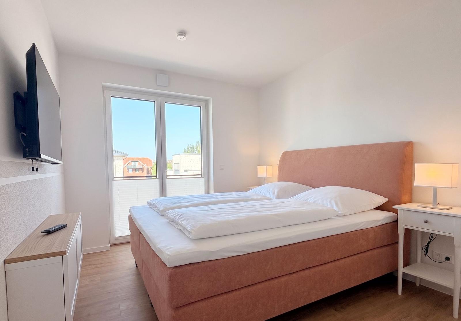 Schlafzimmer mit Bett, TV und Fenster zur Aussicht