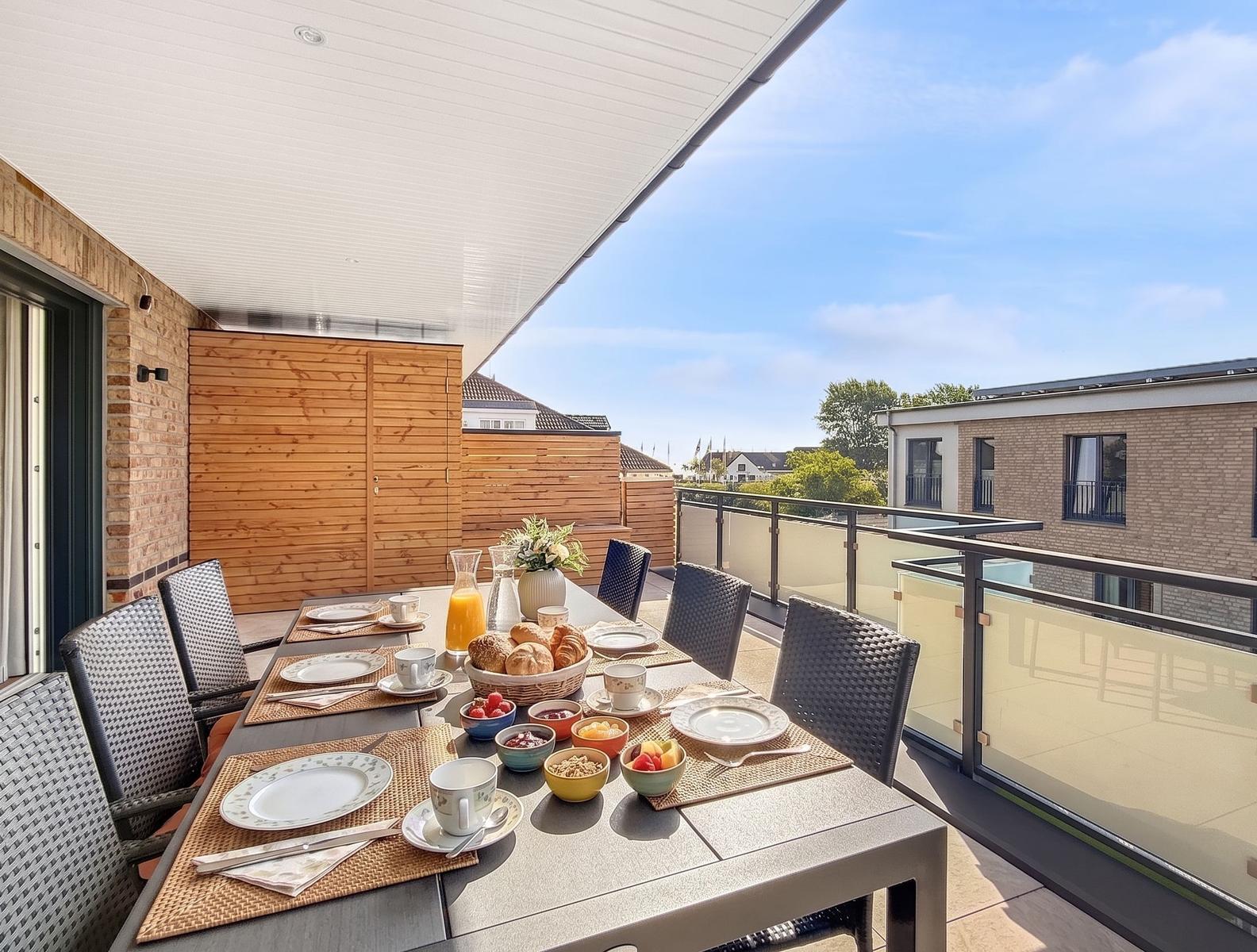 Terrasse mit gedecktem Esstisch und Aussicht auf Wohnhäuser.