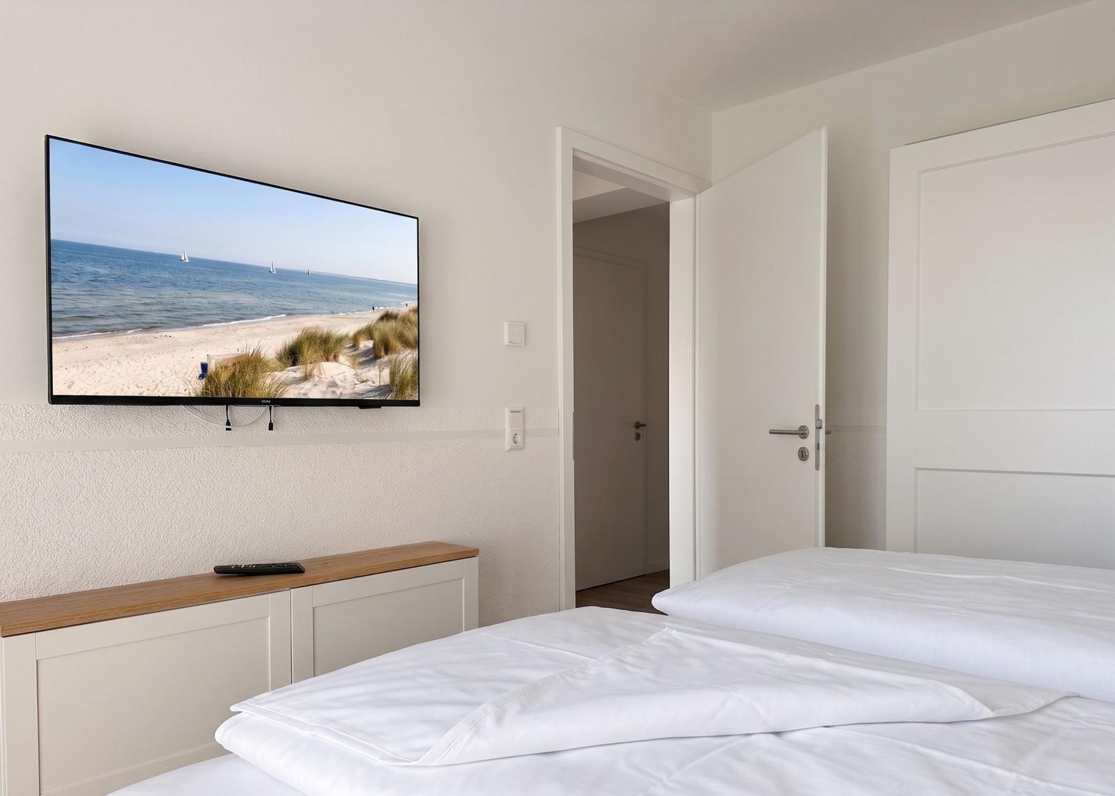 Schlafzimmer mit Bett, Fernseher und Tür