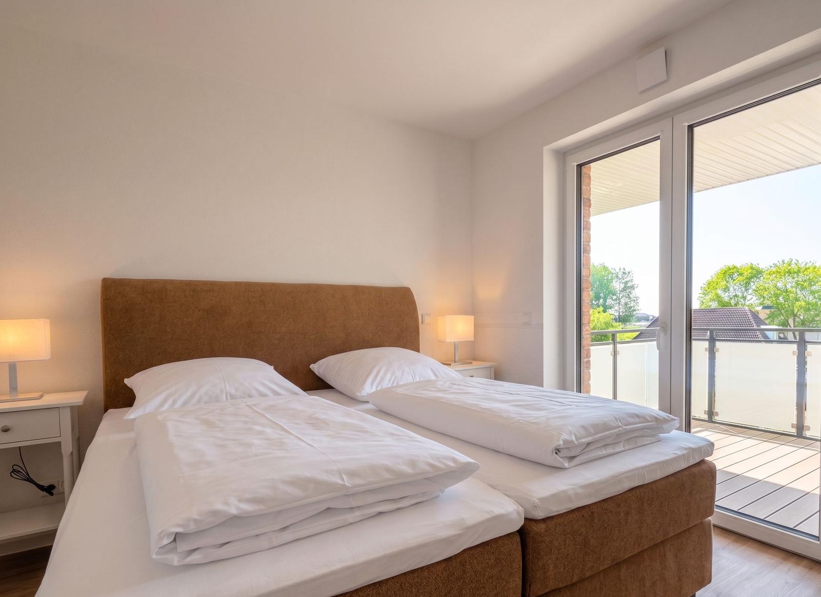 Schlafzimmer mit Doppelbett, zwei Nachttischen und Balkontür.