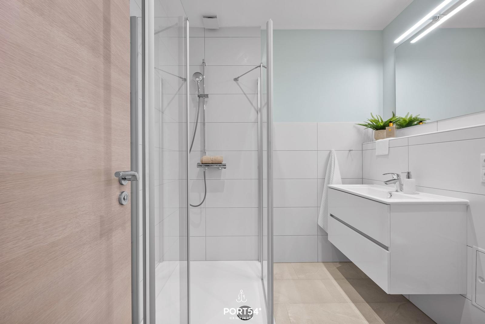 Badezimmer mit Dusche, Waschbecken und Spiegel