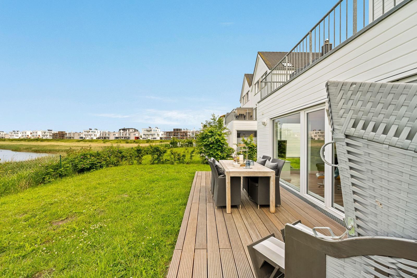 Terrasse mit Tisch und Stühlen, Blick auf Grünfläche und Wohnhäuser.