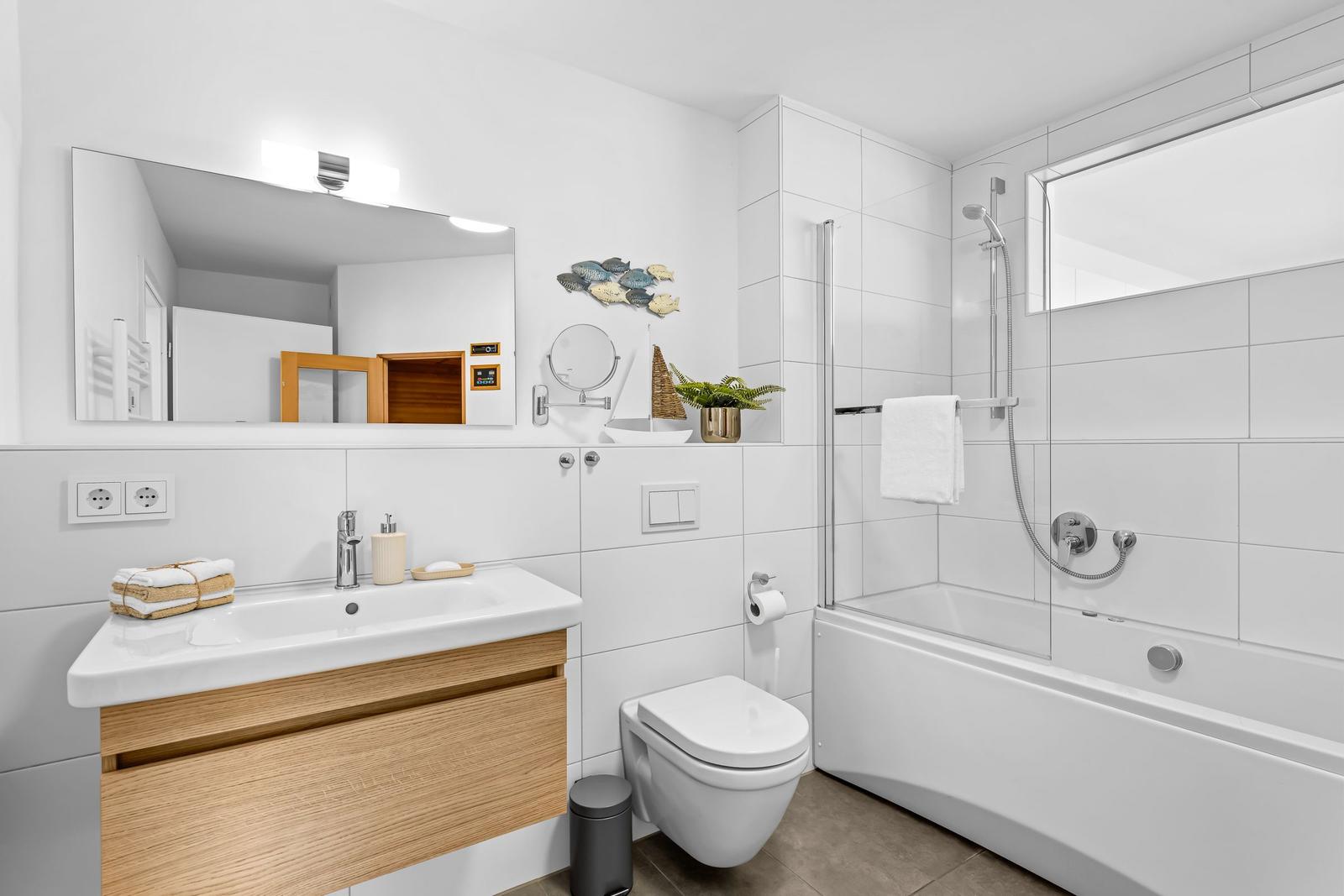 Badezimmer mit Badewanne, Dusche, Waschbecken und Spiegel.