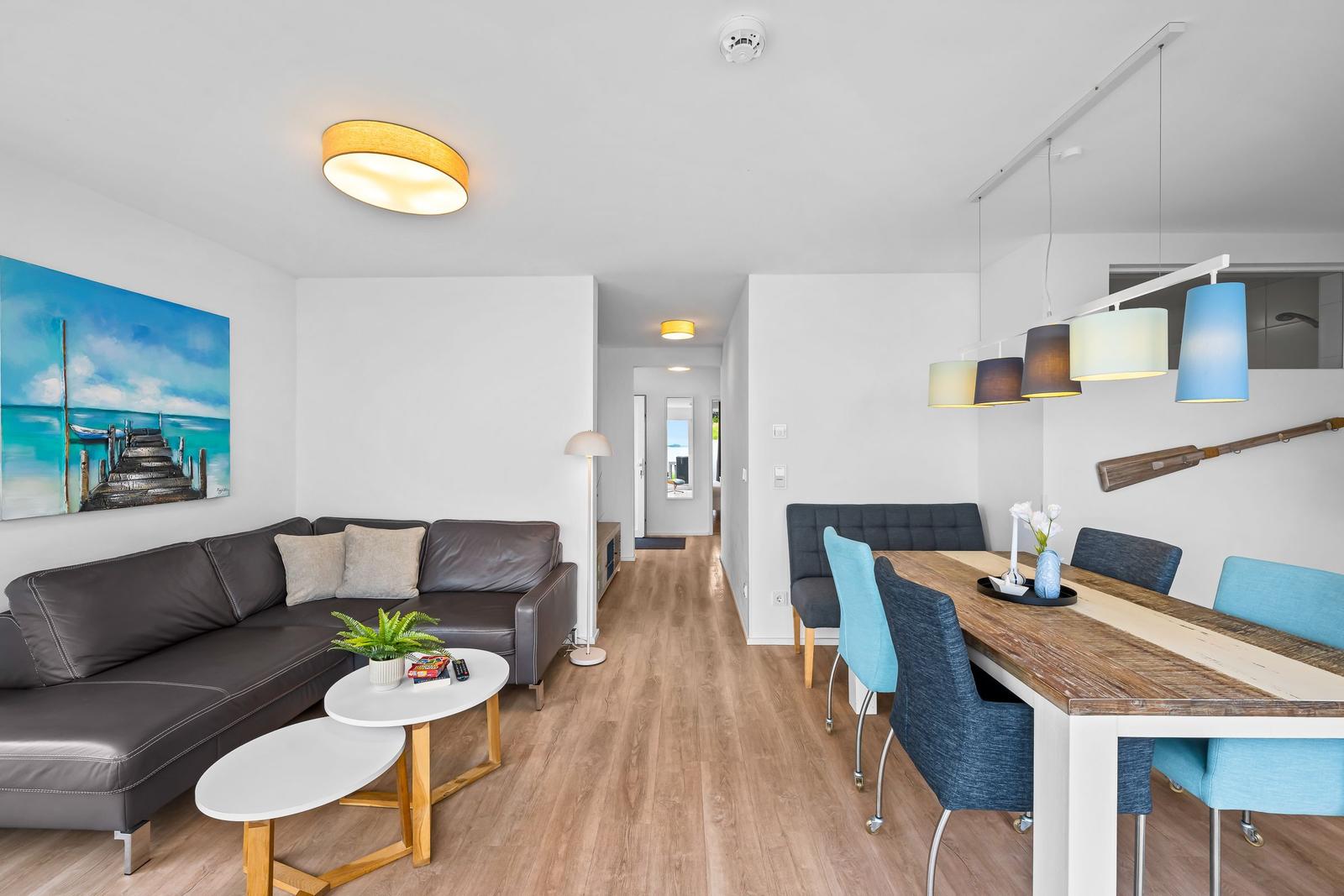 Wohn- und Essbereich mit Sofa, Tisch, Stühlen und Wandbild.