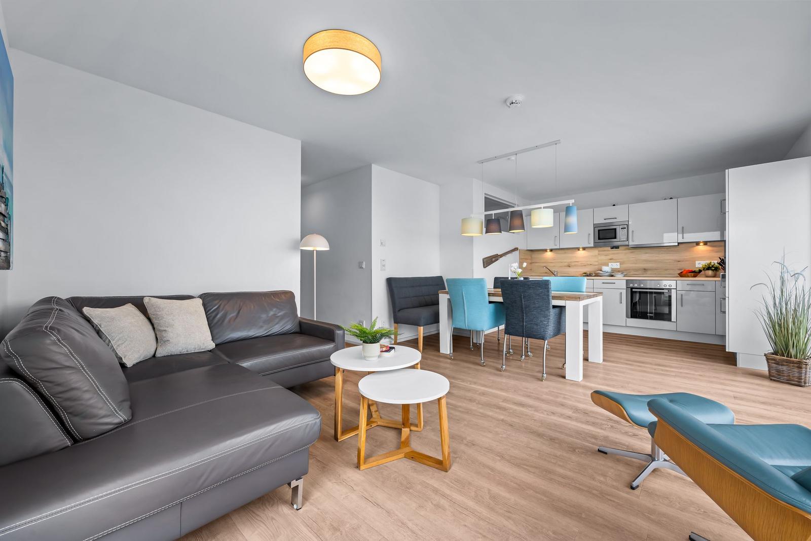 Wohnbereich mit Sofa, Essbereich und Küche. Holzboden und moderne Einrichtung.