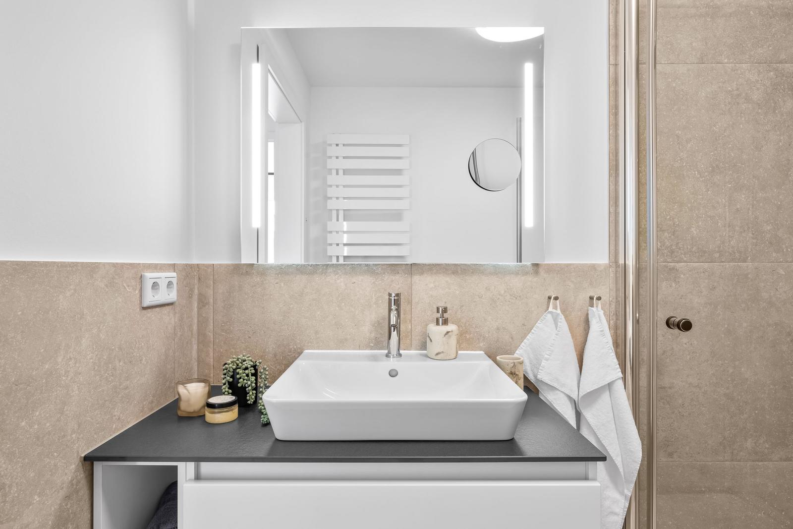 Badezimmer mit Waschbecken, Spiegel und Dusche.
