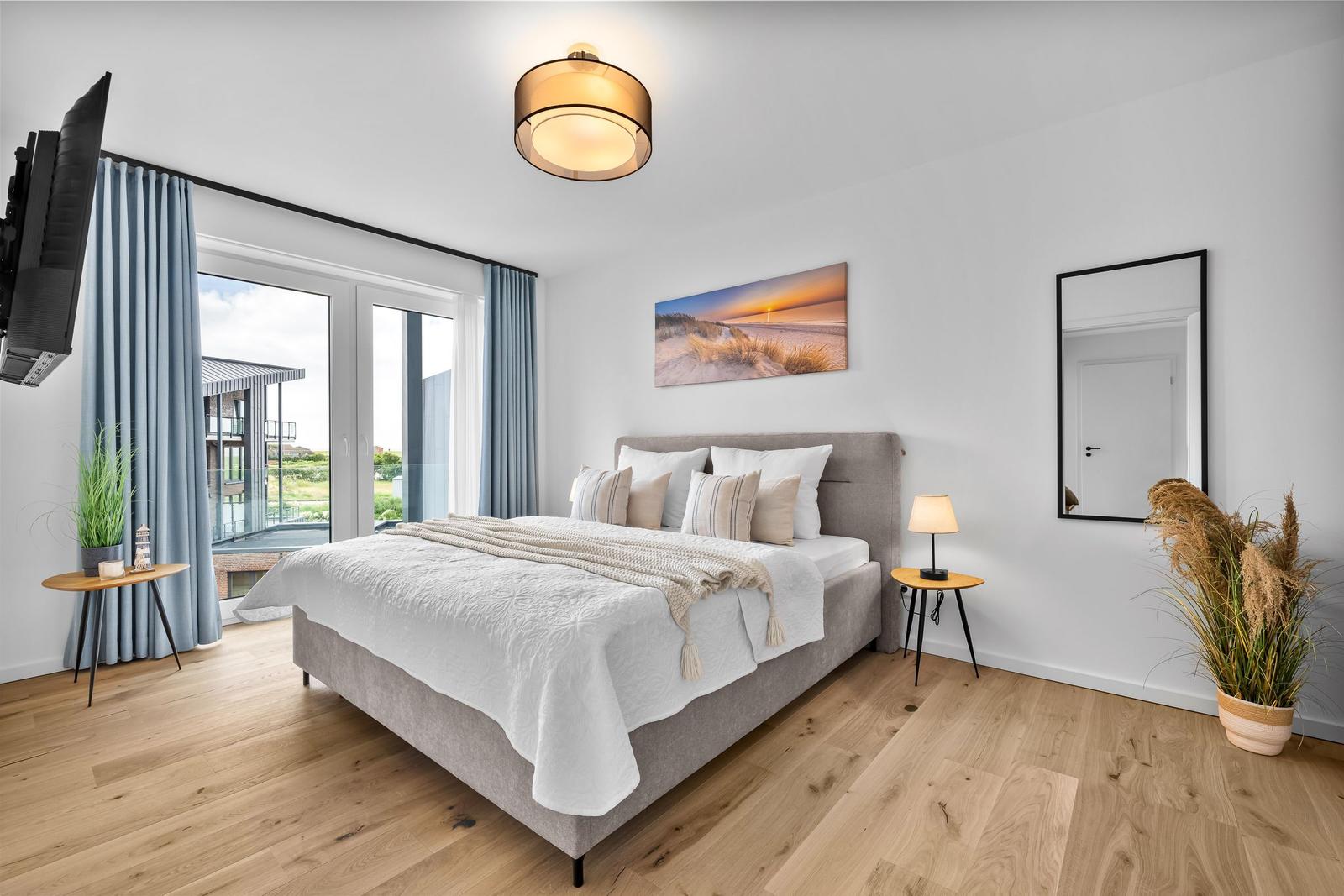 Schlafzimmer mit Bett, TV, Fenster und Wandbild.