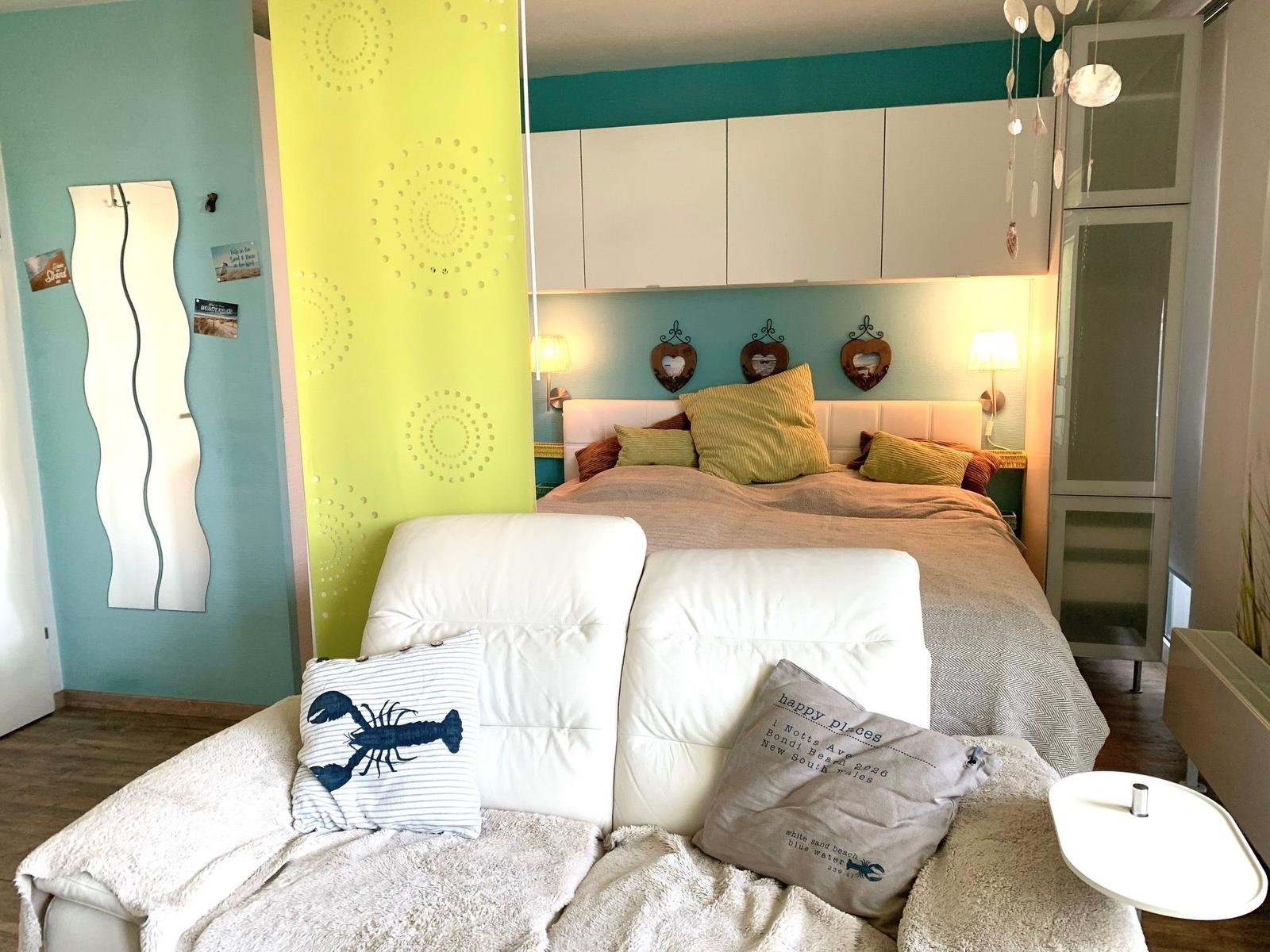 Schlafzimmer mit Bett, Sofa und Wanddekoration.