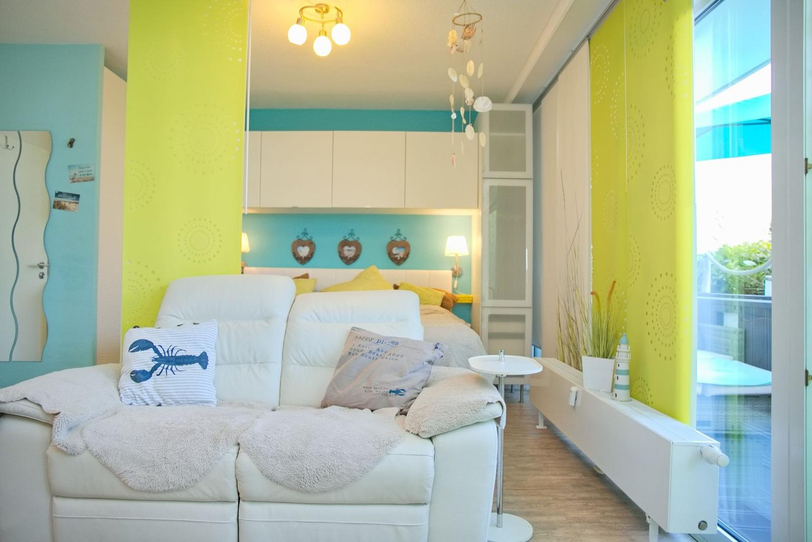 Wohnbereich mit Sofa, Bett und Fenster zur Terrasse