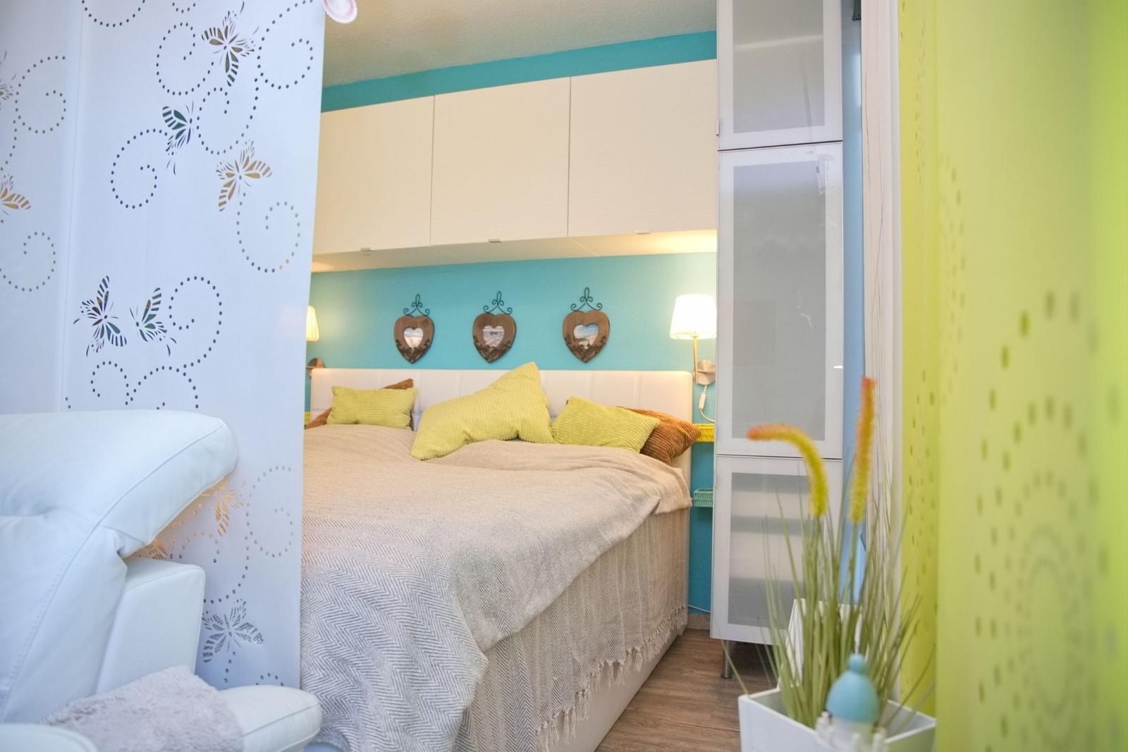 Schlafzimmer mit Bett, Wandregalen und dekorativen Wandelementen.