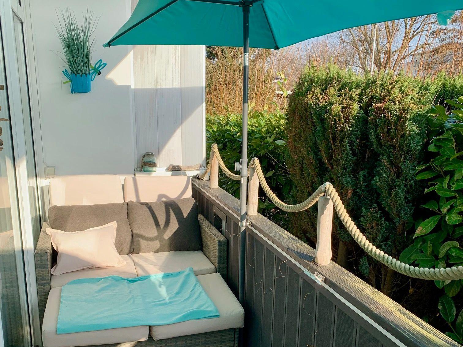 Terrasse mit Sitzbank, Sonnenschutz und Pflanzen. Holzgeländer mit Seilzaun.