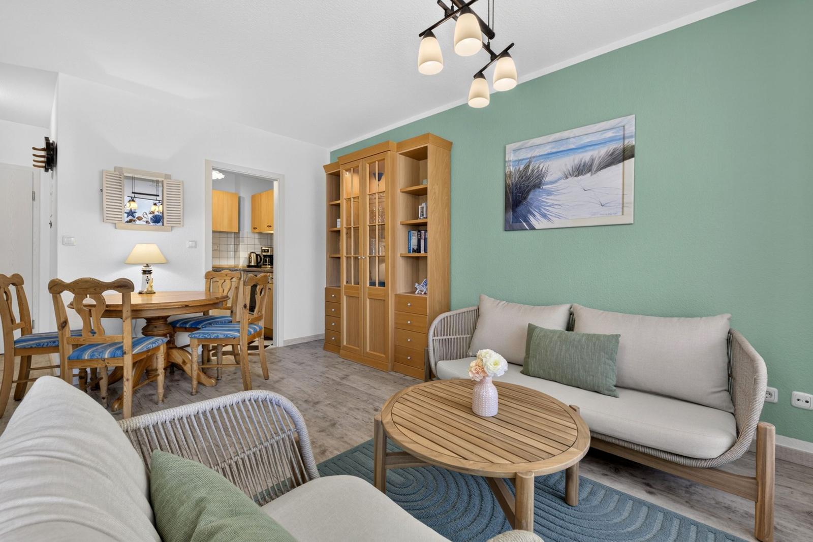 Wohn- und Essbereich mit Sofa, Tisch und Küchenbereich im Hintergrund.