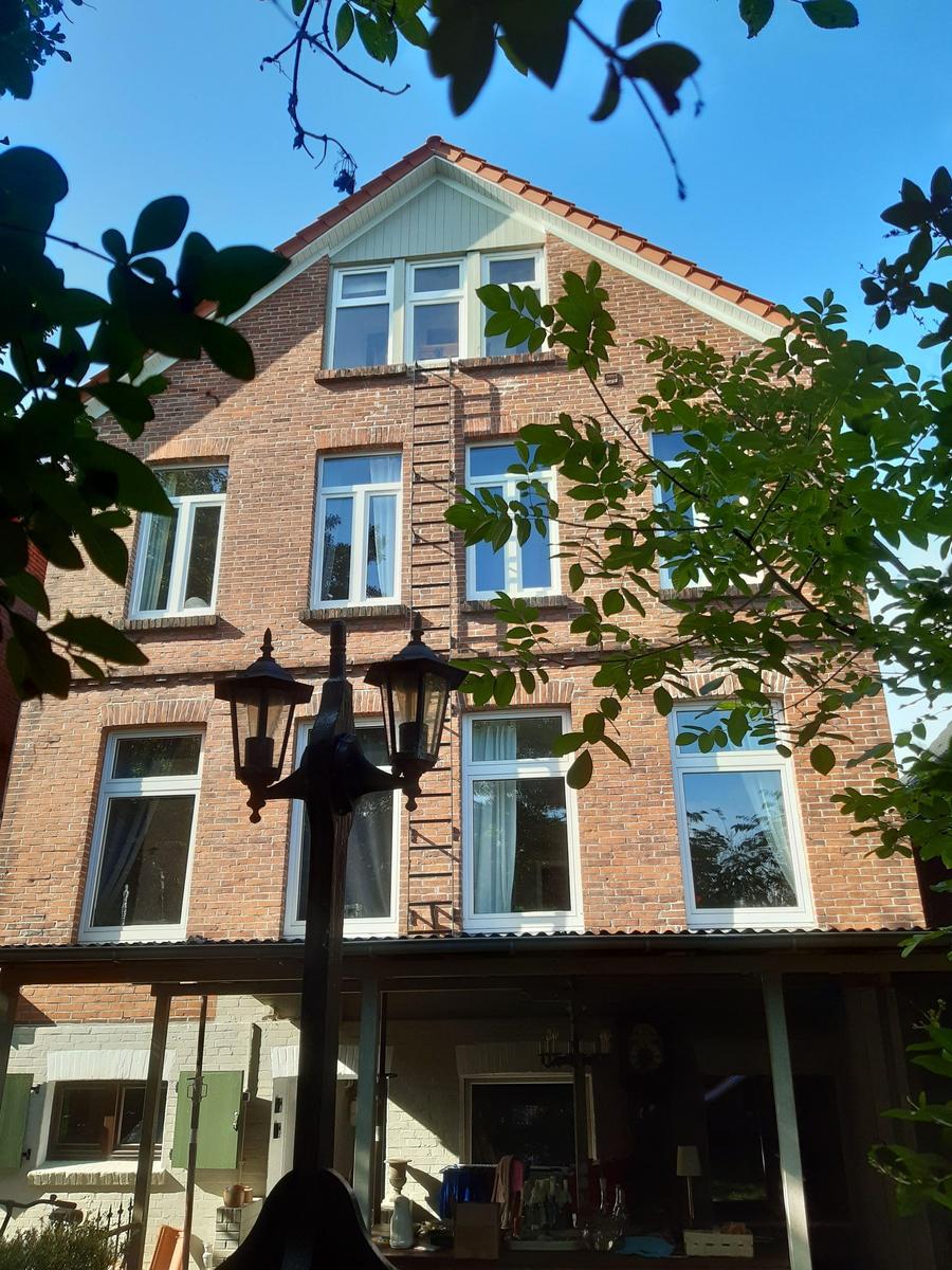 Zweistöckiges Backsteinhaus mit weißen Fenstern und Vorgarten.