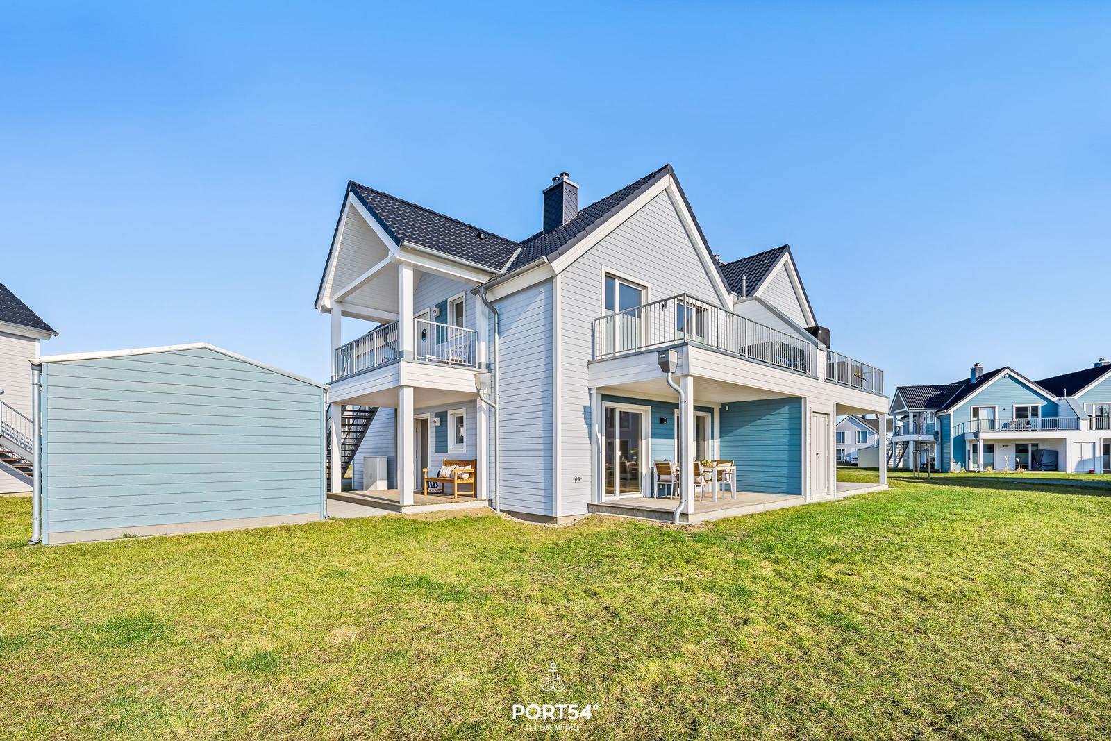 Modernes Ferienhaus mit Balkon und Terrasse. Grünfläche vor dem Haus.