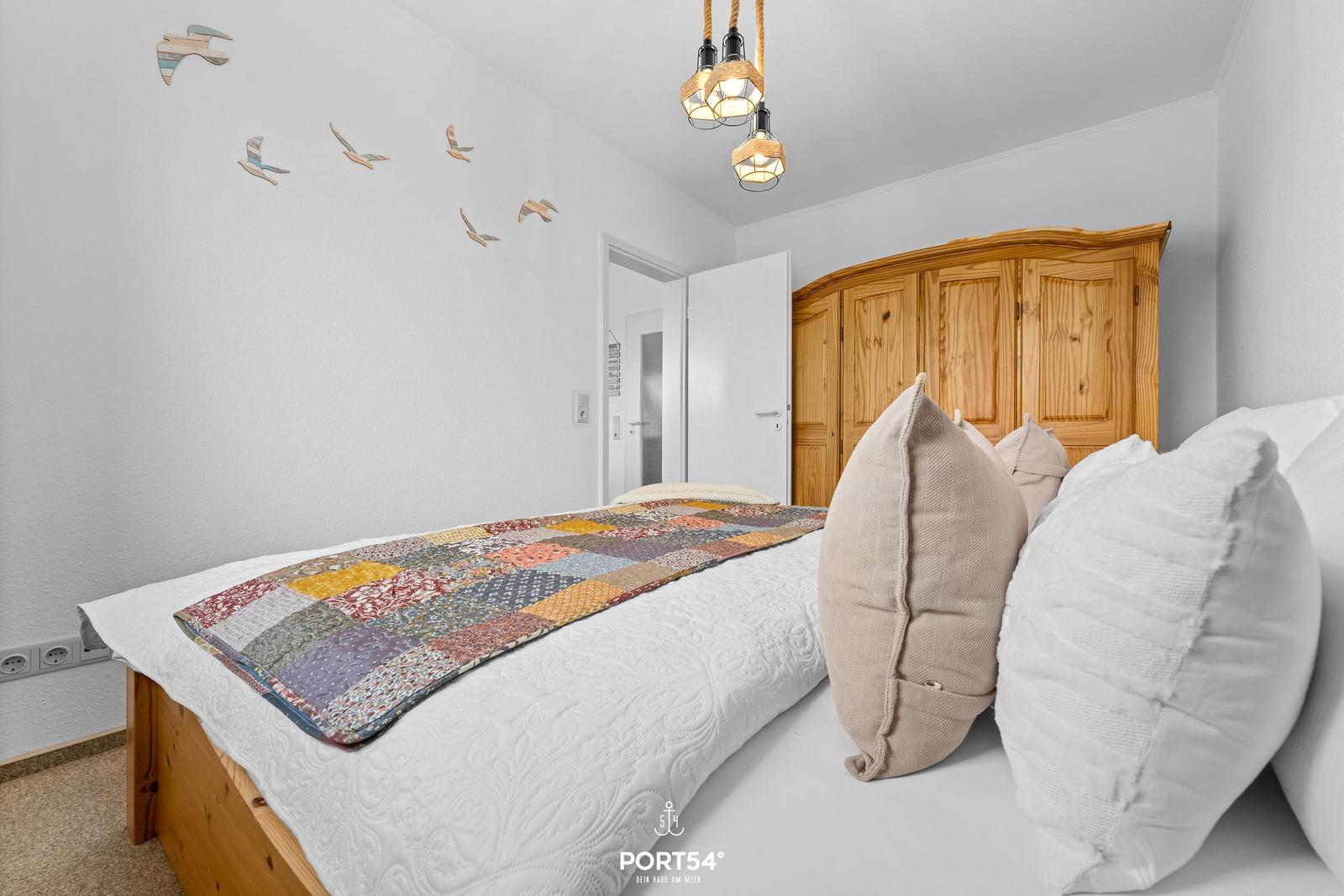 Schlafzimmer mit Bett, Holzschrank und Wanddekoration
