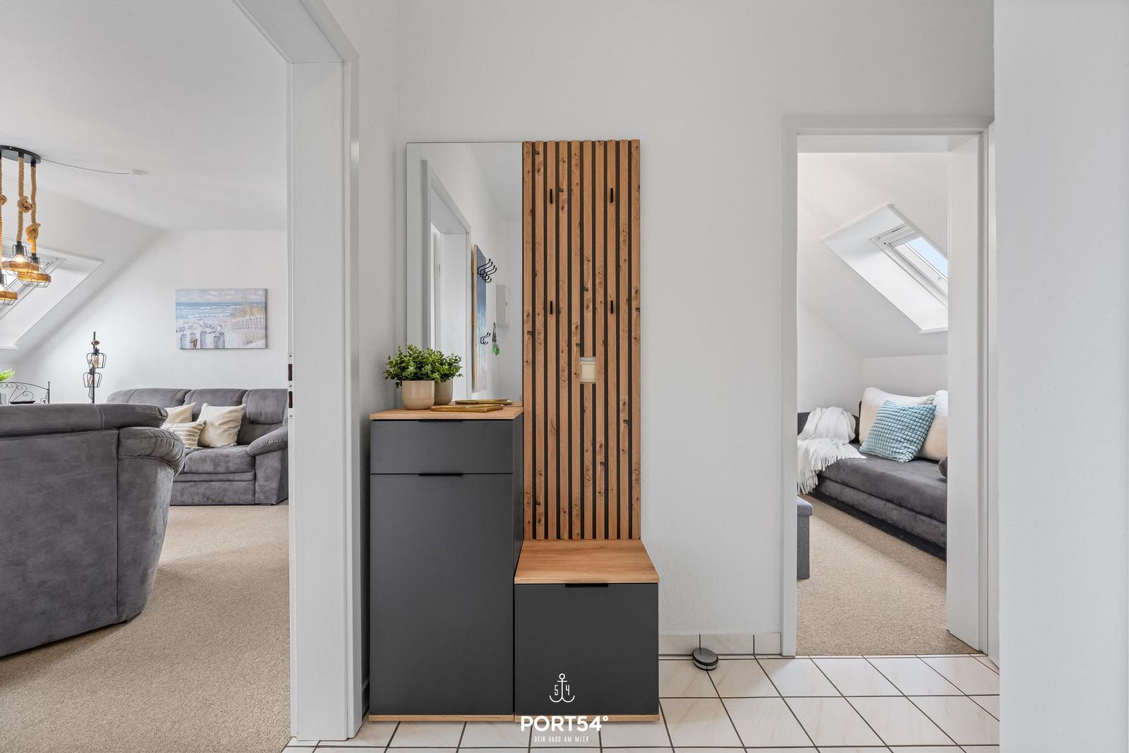 Eingangsbereich mit Spiegelschrank und Holzpaneelen. Blick in Wohnzimmer und Schlafzimmer.