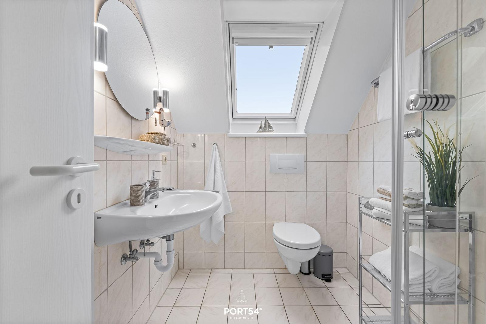 Badezimmer mit Waschbecken, Toilette und Dusche unter Dach
