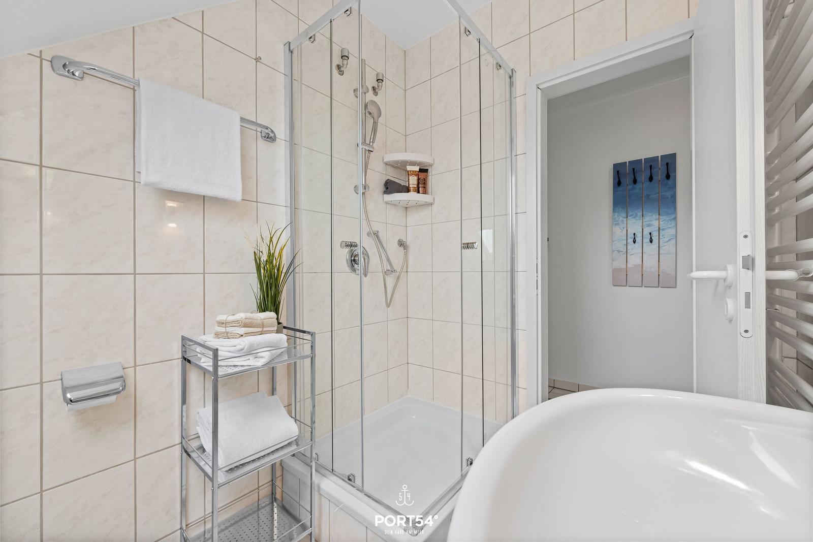 Bad mit Dusche, Badewanne und Handtuchständer.