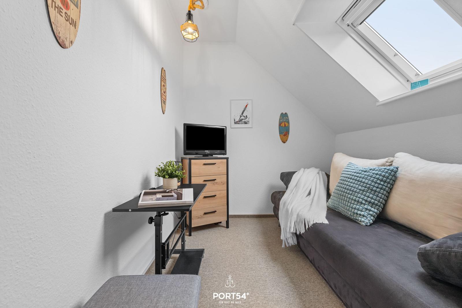 Dachgeschosszimmer mit Sofa, Fernseher und Dachfenster.
