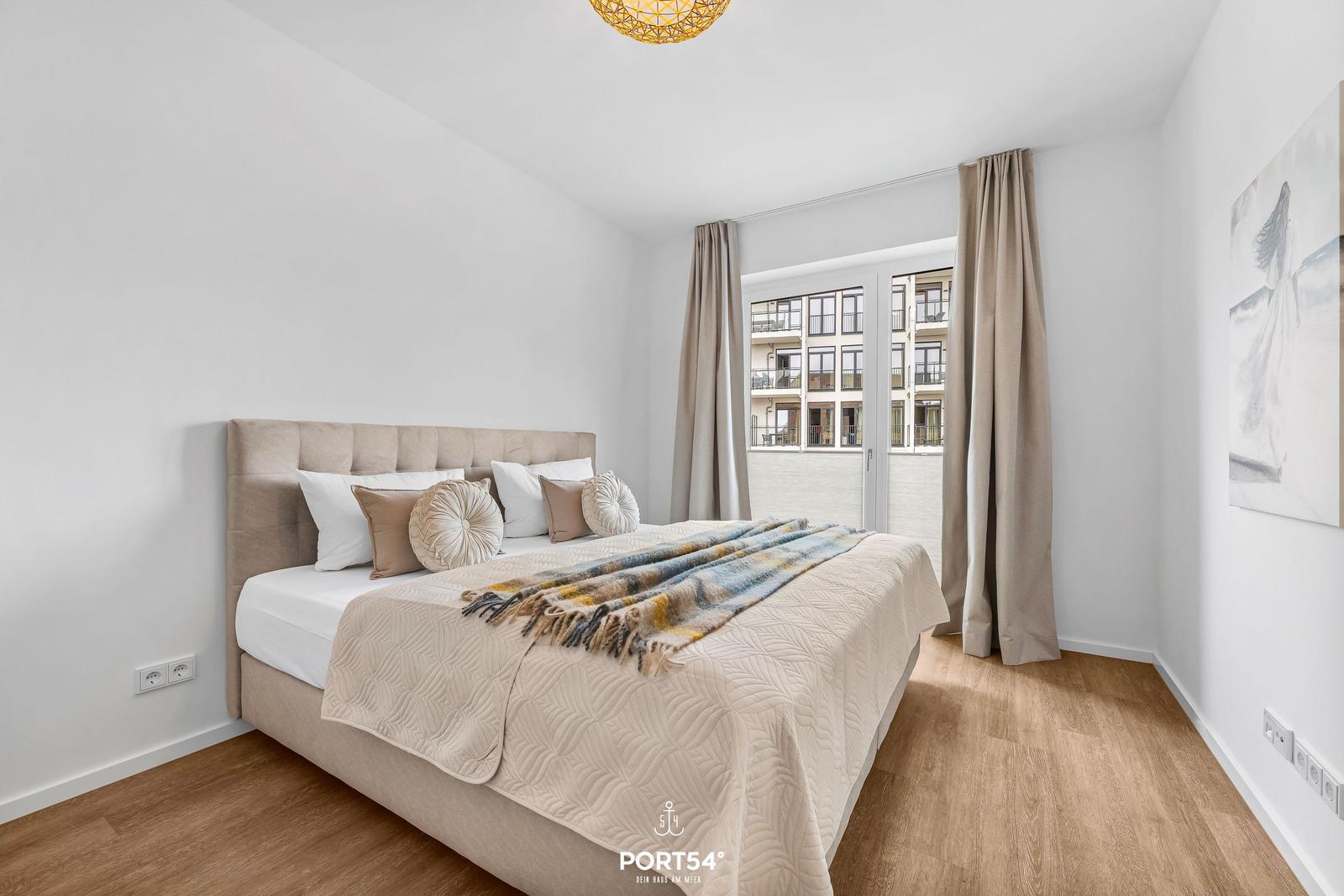 Bedroom with bed, curtains, and view of balcony.
