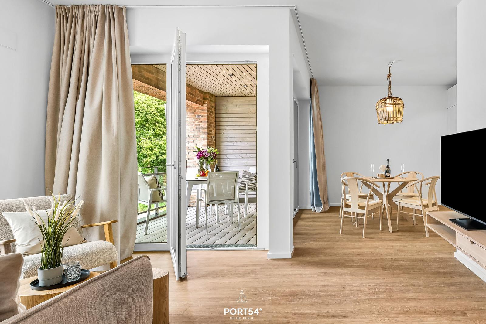 Living and dining area with terrace. Wooden floors, modern furnishings, and view of greenery.