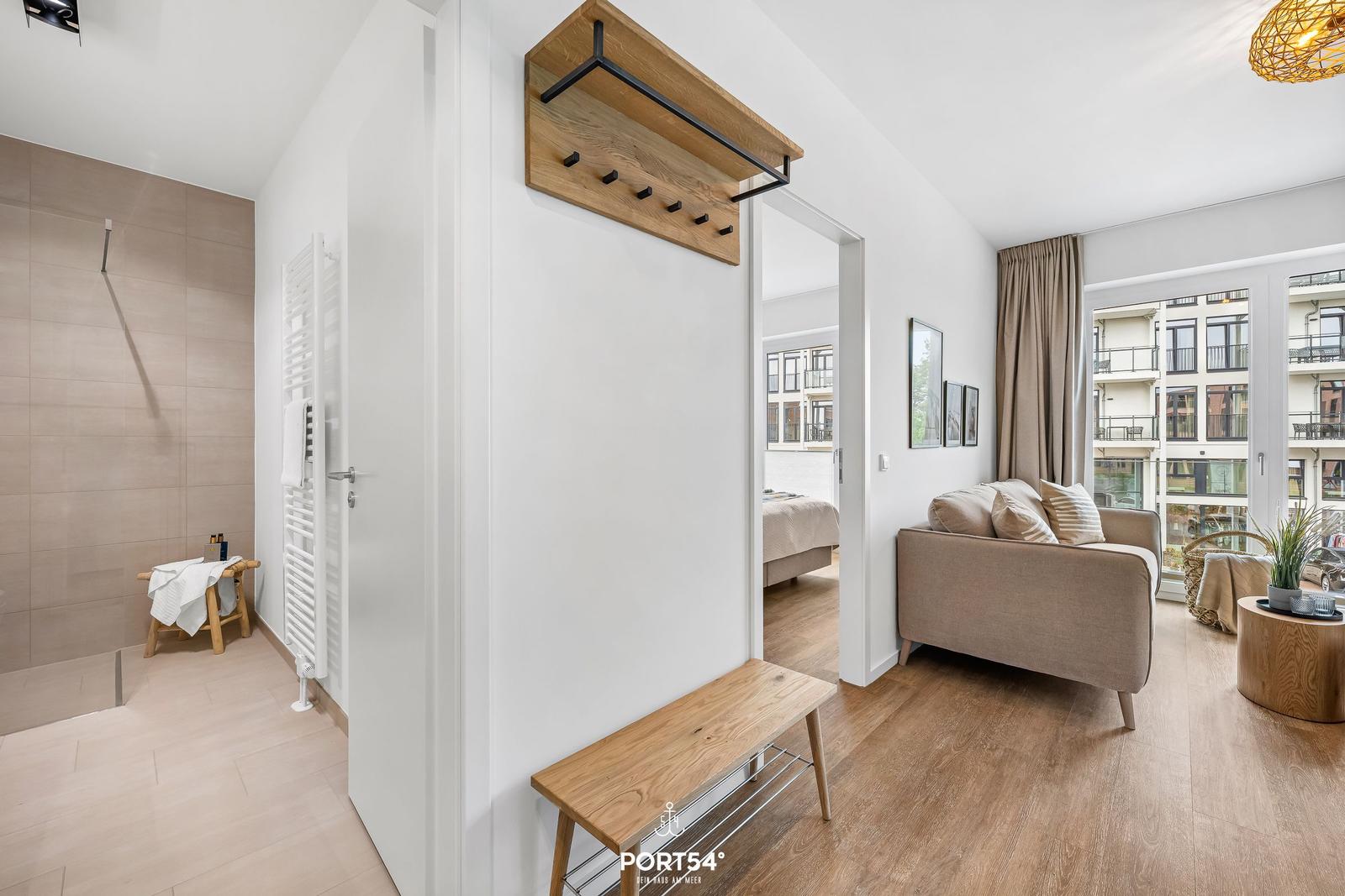 Entrance area with coat rack, hallway, and view into living room and bathroom.