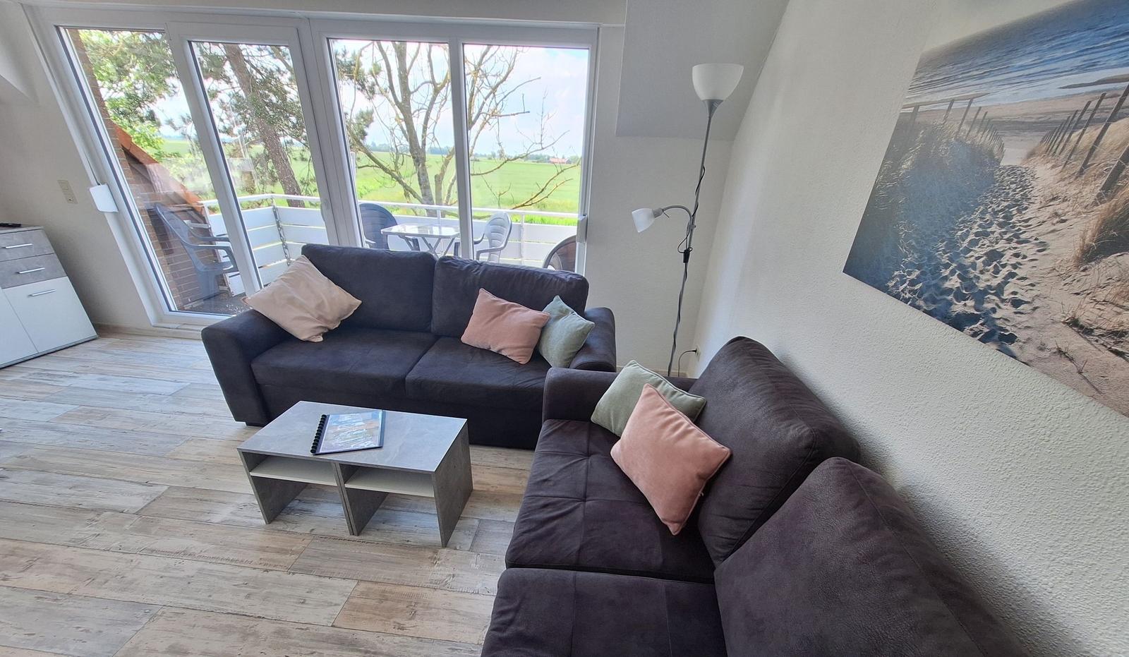 Wohnzimmer mit Sofa, Couchtisch und Blick auf Balkon.