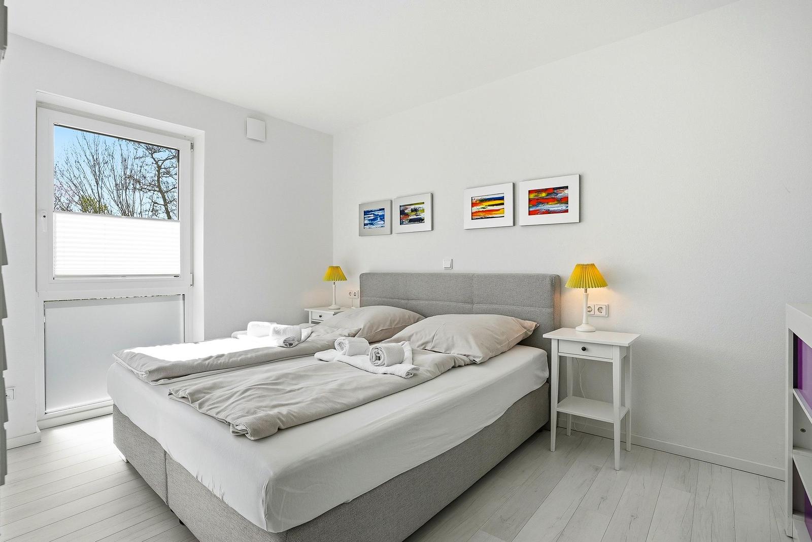 Schlafzimmer mit Doppelbett, zwei Nachttischen und Fenster mit Blick nach draußen.