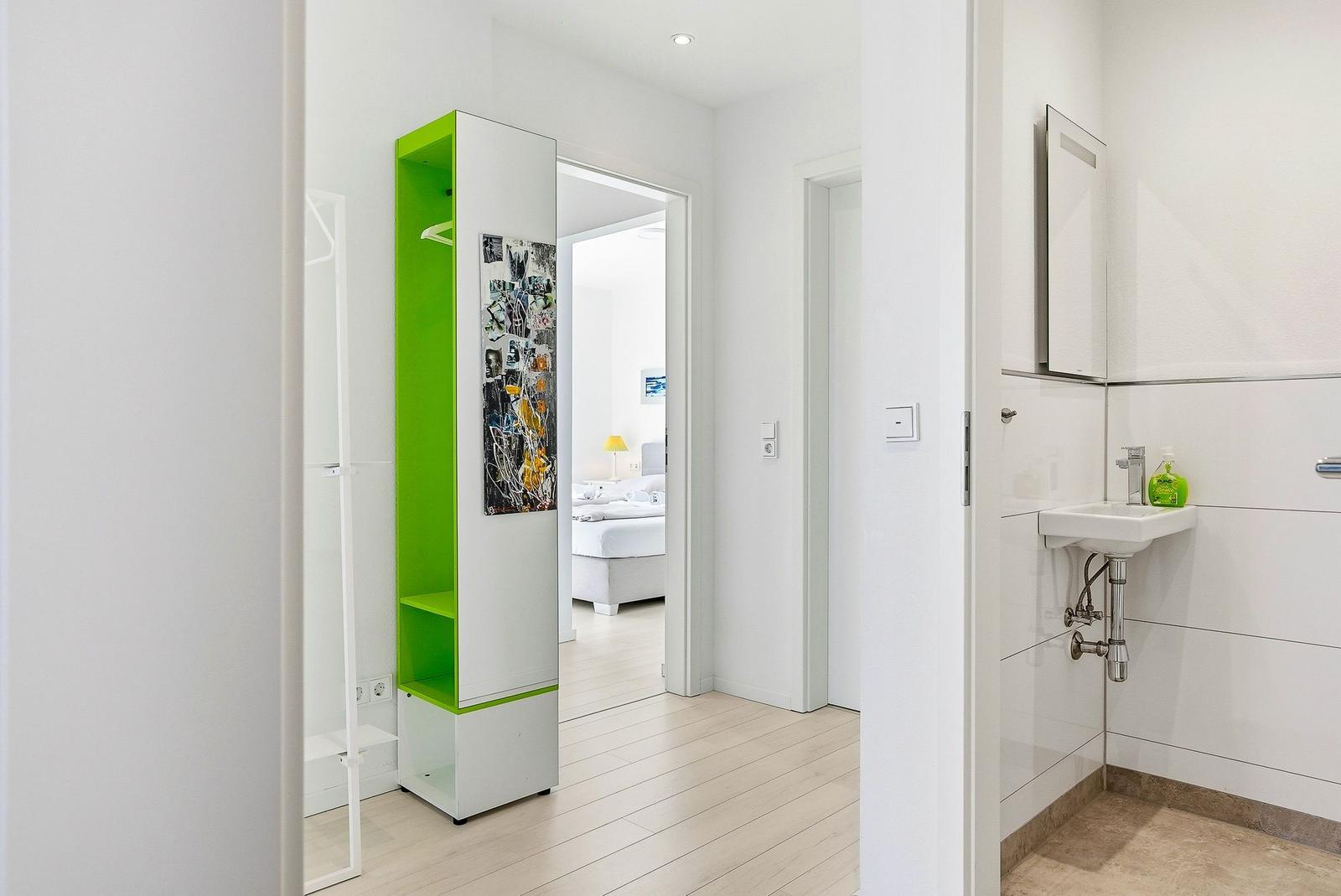 Flur mit grünem Schrank, Schlafzimmer und Bad mit Waschbecken