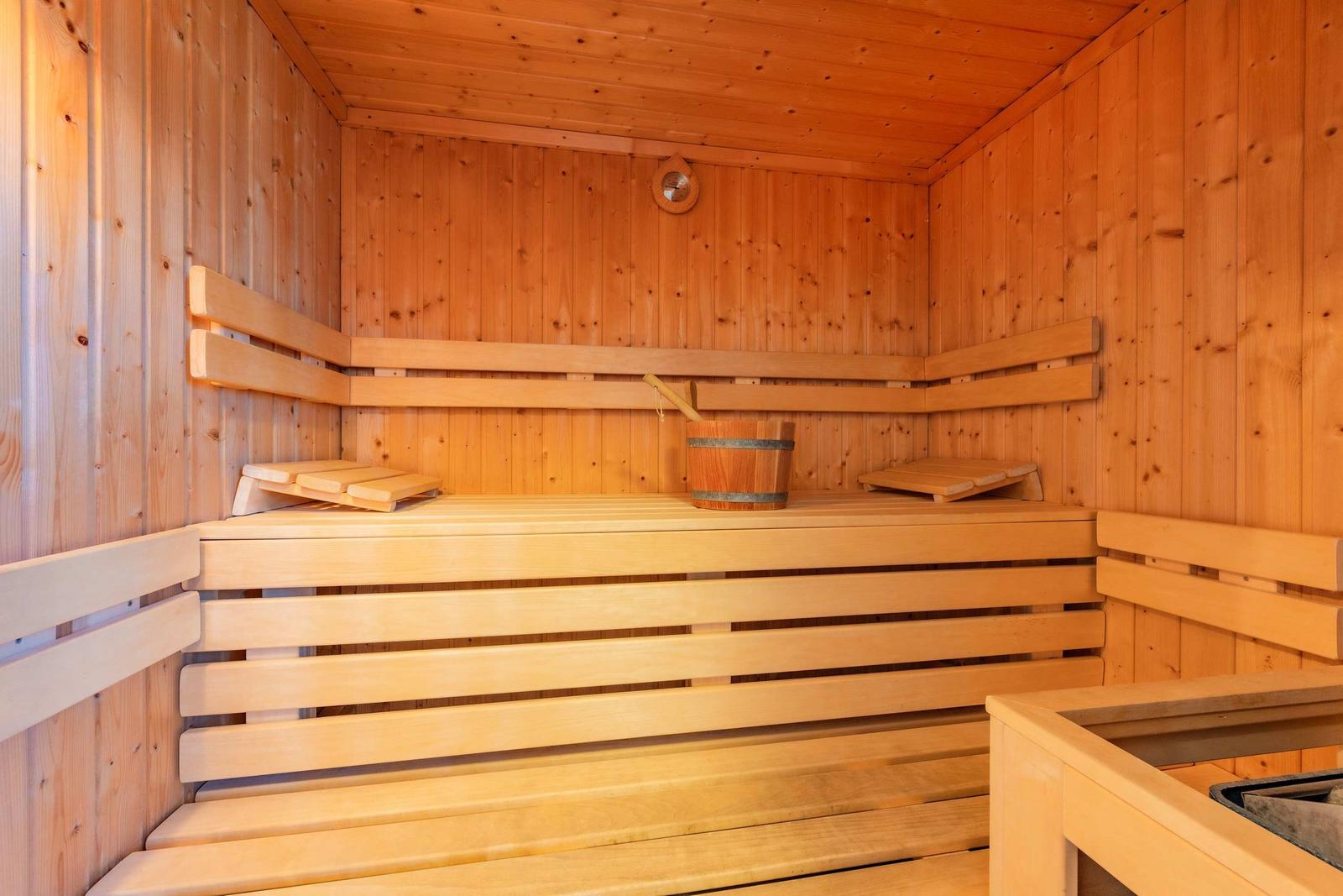 Holzsauna mit Sitzbänken und Eimer. Decke und Wände aus Holz.